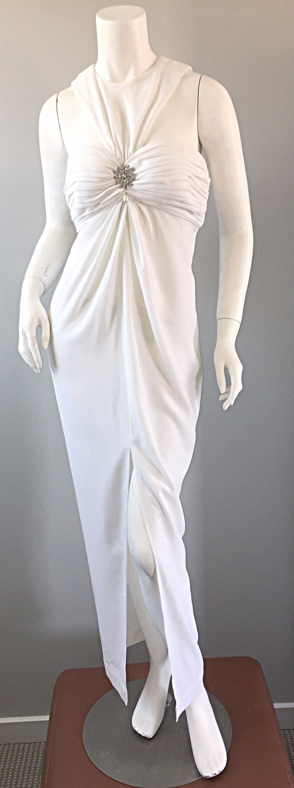 Sexy vintage Tadashi Shoji white dress! Avant Garde style, with cut-outs at bust (on front and back). Attached rhinestone brooch at bust, encrusted with an oversized pearl dangling from the bottom. Ruching at bust, and slit up the front. A definite