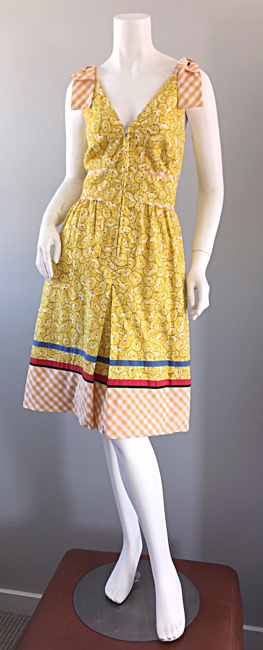 So ein schickes 90er Jahre Vintage-Kleid von Cacharel! Durchgehend gelber Mohndruck, gemischt mit Gingham am Saum, an der Taille und an den Schulterschleifen. Reißverschlüsse an der Vorderseite. Schöne, schlankmachende Passform. 100% Baumwolle.