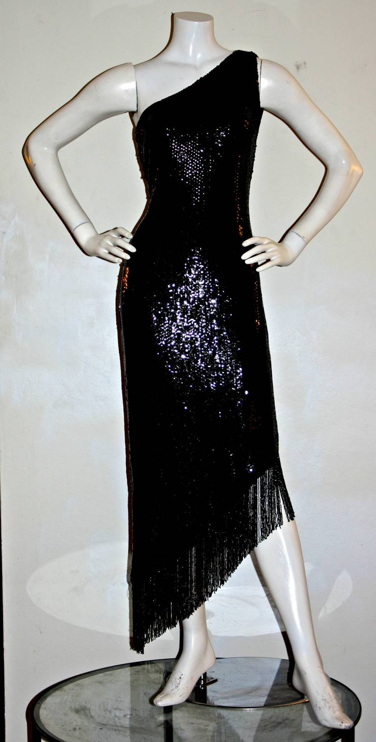 Featuring an ultra sexy vintage Bill Blass one-shoulder black sequin dress! Asymmetrical hem, with beaded fringe. Looks fantastic on the dance floor! In great condition. Approximately Size Small

Measurements:
34 inch bust
28 inch waist
38 inch