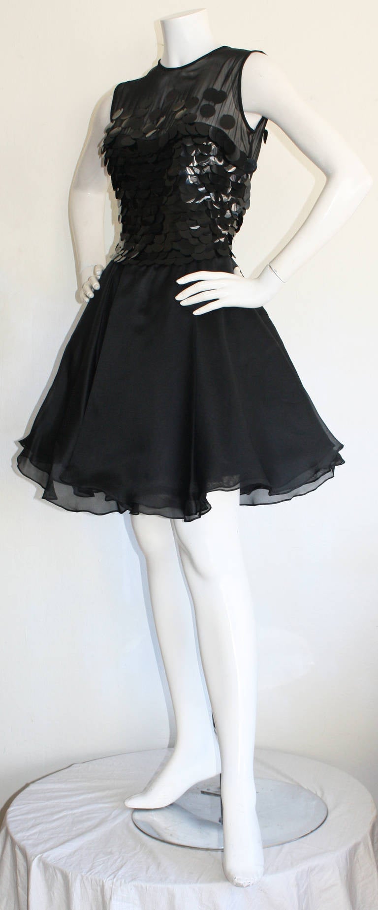 Simply stunning vintage disc dress by CD Greene! The perfect little black dress!!! Features black disc sequins, with sweetheart neckline on semi sheer silk. Skirt features layers and layers of black chiffon, with built in crinoline. Sexy peek-a-boo