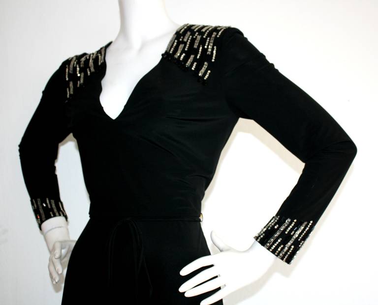 Beautiful black silk jersey dress by Mr. Blackwell 'Custom.' Sparkling rhinestones and beads adorn the shoulders and arm cuffs. Original removable rope belt. Stunning fit, and in great condition. Approximately Size XS-S
Measurements:
34-38 inch