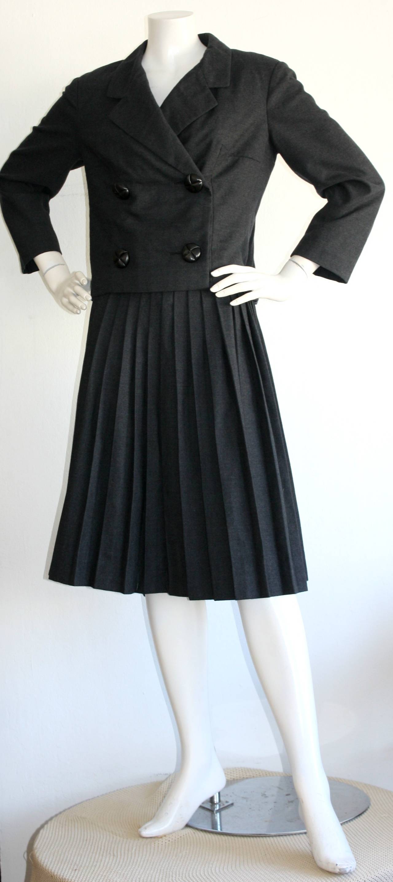 Rare, iconic vintage Christian Dior Charcoal Grey skirt suit from the 1960s! Wonderful pillbox cropped jacket, with full accordion pleated skirt. Chic oversized Double Breasted buttons on jacket. Also features original Neiman Marcus label. Fully