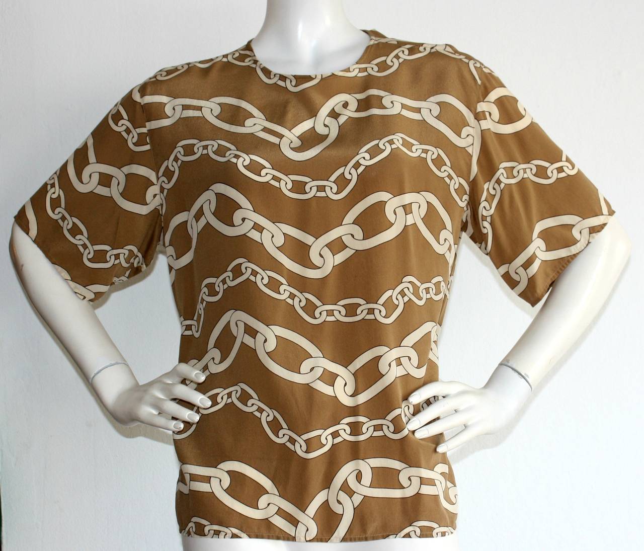 Vintage Valentino blouse, featuring chic iconic chain/rope print throughout. 100% silk, in a taupe/beige combination. Can easily be dressed up or down. Three buttons up the back neck. In great condition. Marked Size US 8

Measurements:
44 inch