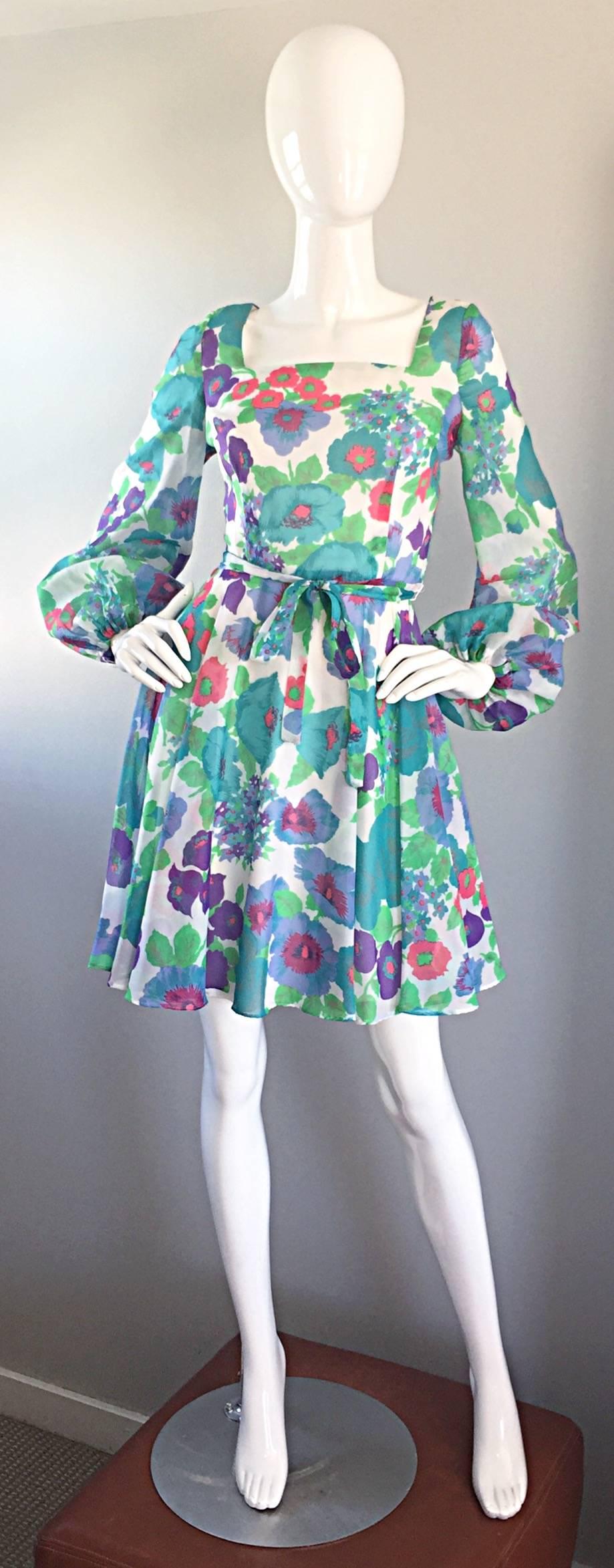 Adorable 60s babydoll dress! Features an allover floral print in blue, green, pink, purple and white! Detachable tie belt at waist. Wonderful full poet sleeves with elastic at wrists. Flattering full skirt with a fitted bodice. Full metal zipper up