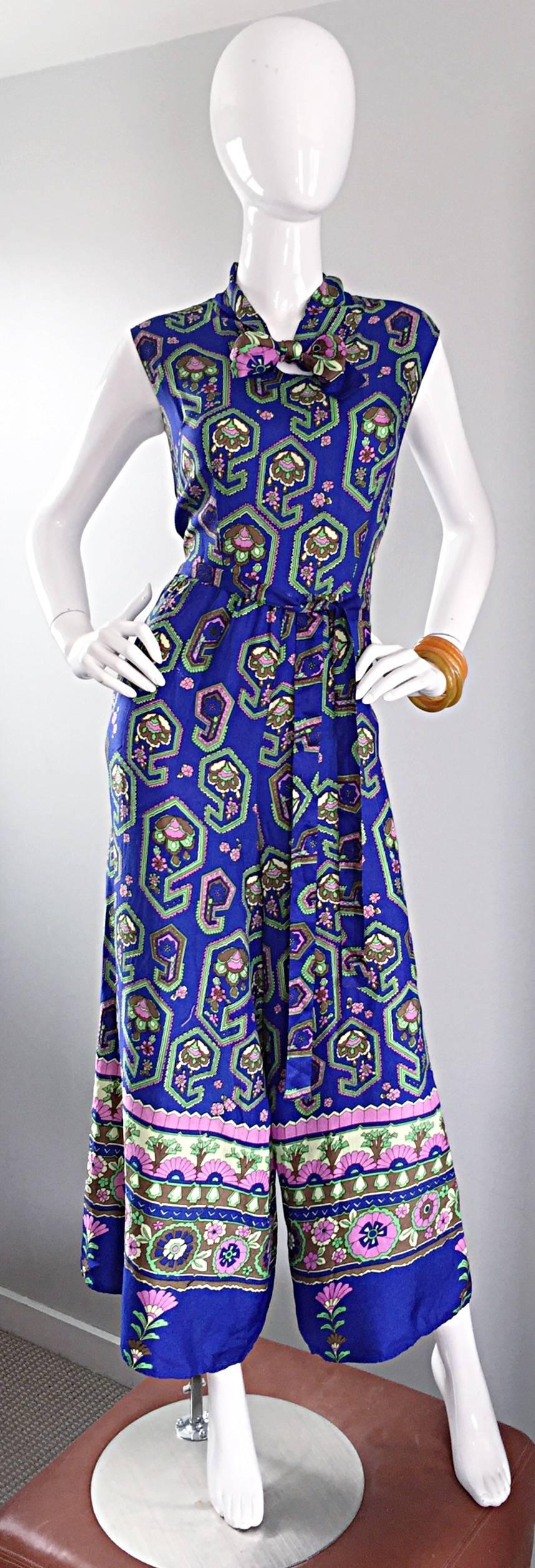 Phenomenal 70s wide palazzo leg jumpsuit! Vibrant blue color with multi color geometric paisley print throughout. Detachable sash belt. Pussycat bow above bust. Pockets at both sides of the waist. Hidden zipper up the back. No fabric tag, but feels