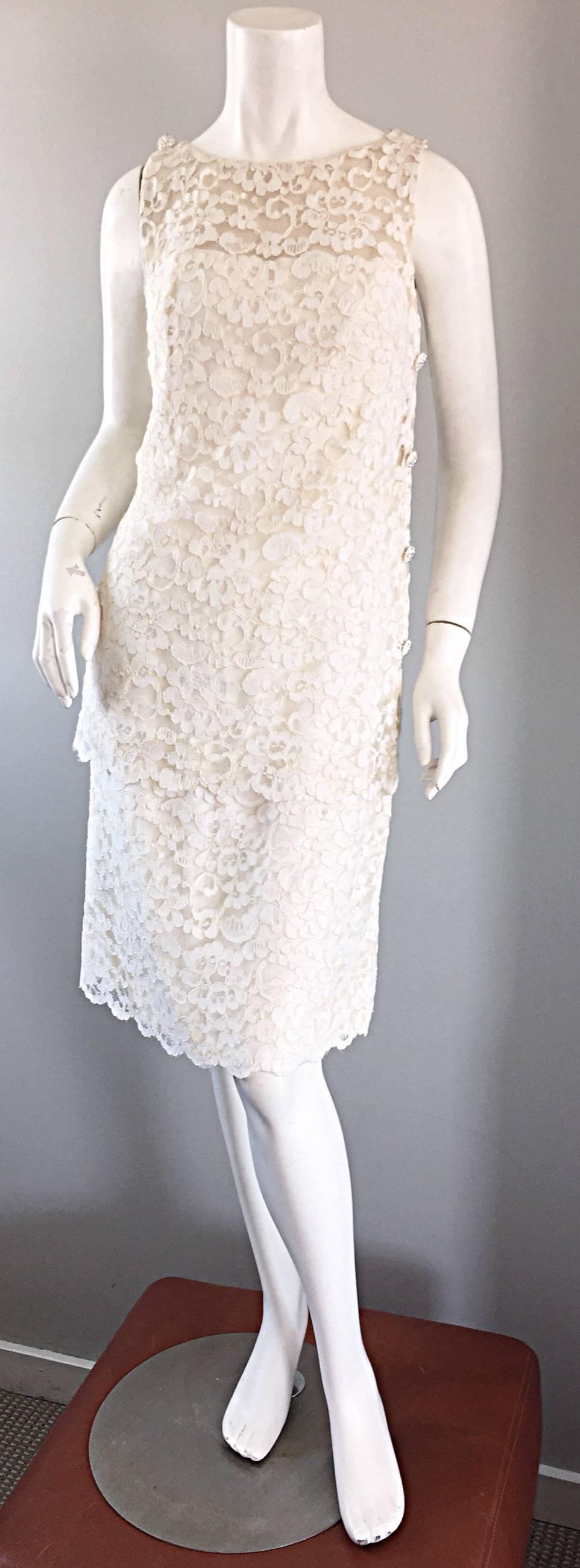 Wunderschönes 1960er LISA HOWARD Kleid aus weißer französischer Spitze, mit Strassknöpfen! Mit zwei Lagen weißer Spitze und einem nackten Illusionshintergrund über der Büste. Weiße, strassbesetzte Scheinknöpfe an der Seite und an jeder Schulter. Die
