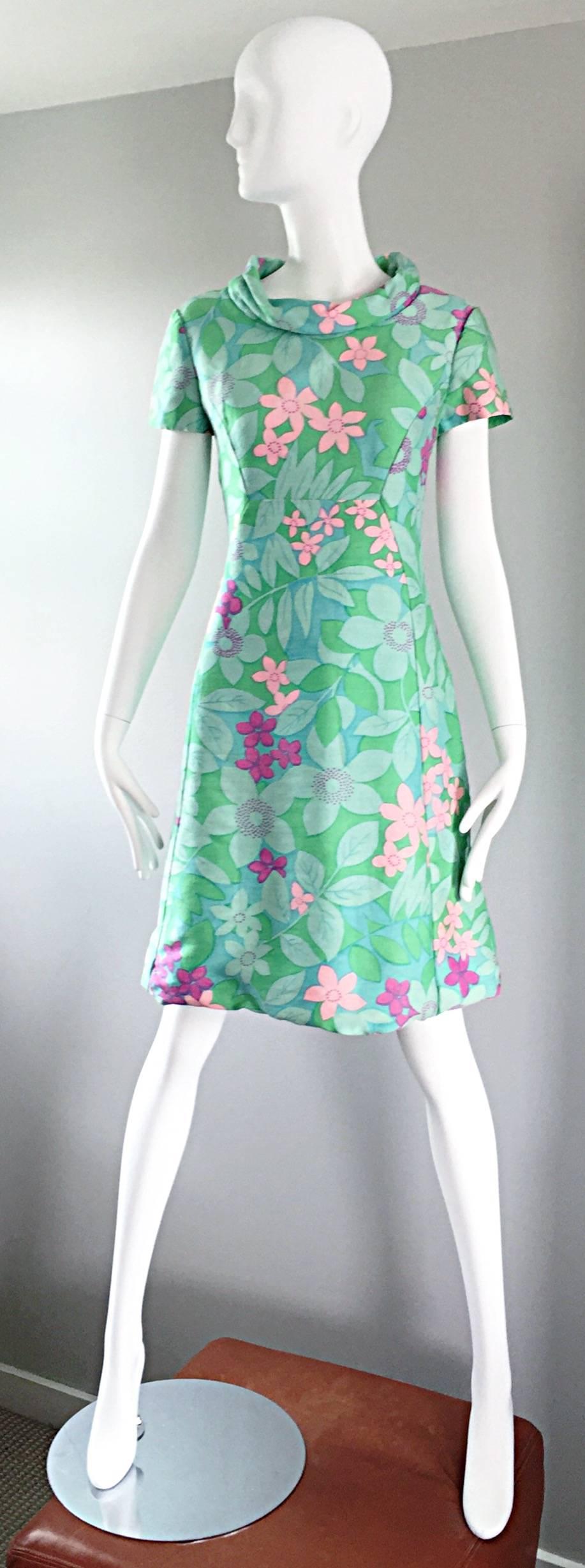 Such a chic and adorable vintage 1960s ADELE SIMSPON Jackie-O style       A-Line dress! Features pastel colors of green, pink, blue and purple in a whimsical flowers and leaves print. Tailored short sleeves, with a bit of a cowl neckline. Full