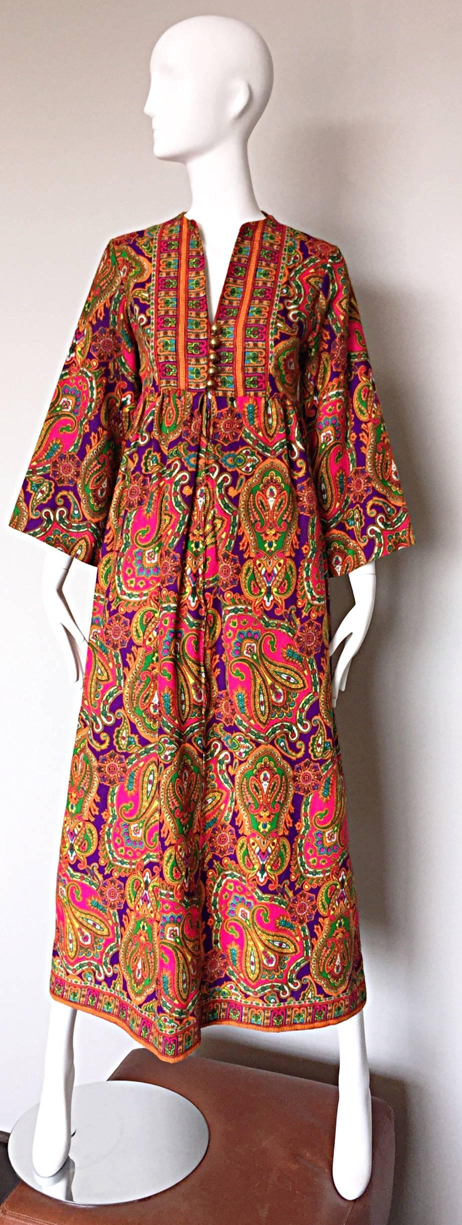 Wonderful vintage 1970s JOSEPH MAGNIN colorful paisley kaftan / maxi dress! Features an allover regal paisley print in pink, purple, green, orange, blue and gold throughout. V-neckline with golden ball buttons up the bodice, with a hidden zipper
