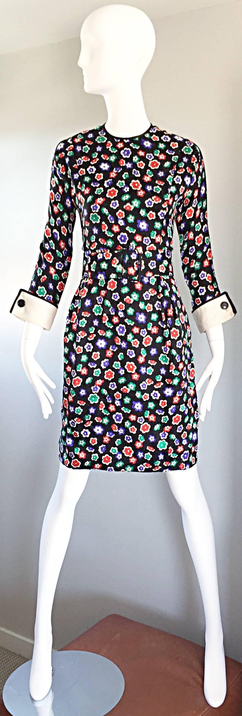 Chic vintage GEOFFREY BEENE black long sleeve dress with red, blue, green, and white printed flowers throughout. Pockets at both sides of the waist. Features a detachable belt, and white French cuffs. Extremely well made, with interior strap at