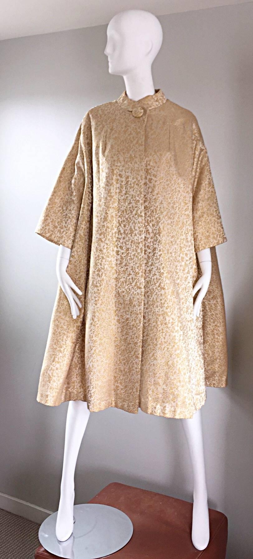 Sensational vintage 50s trapeze/opera jacket by THE SURPRISING DRESS-ETERIA! Features an allover gold metallic and ivory printed silk brocade! Simple stunning fit that will accommodate nearly any size from Small - XL! One singular button at collar.