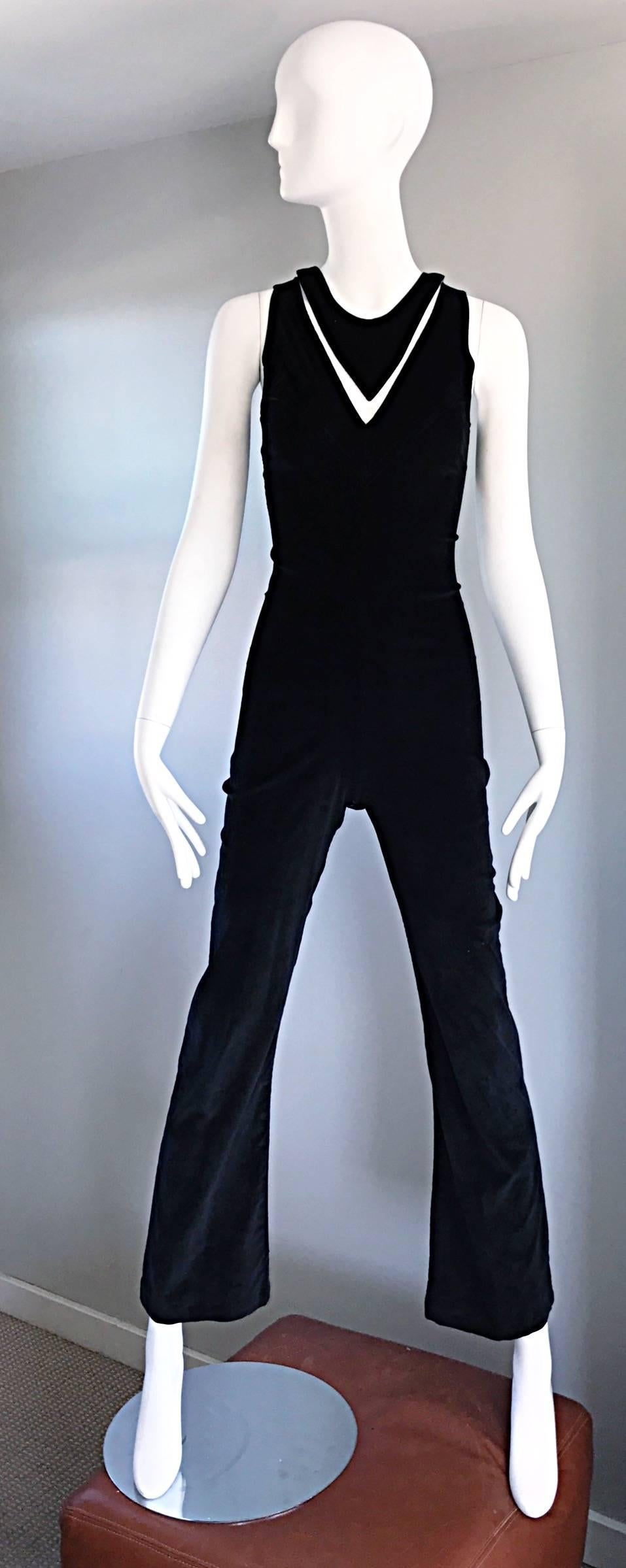 Incredible vintage 1970s black fine cotton corduroy flared leg jumpsuit! Features a space age cut-out at the neckline. Soft thin cotton corduroy feels amazing against the skin! Fitted bodice and legs, with a flared leg opening. Hidden zipper up the