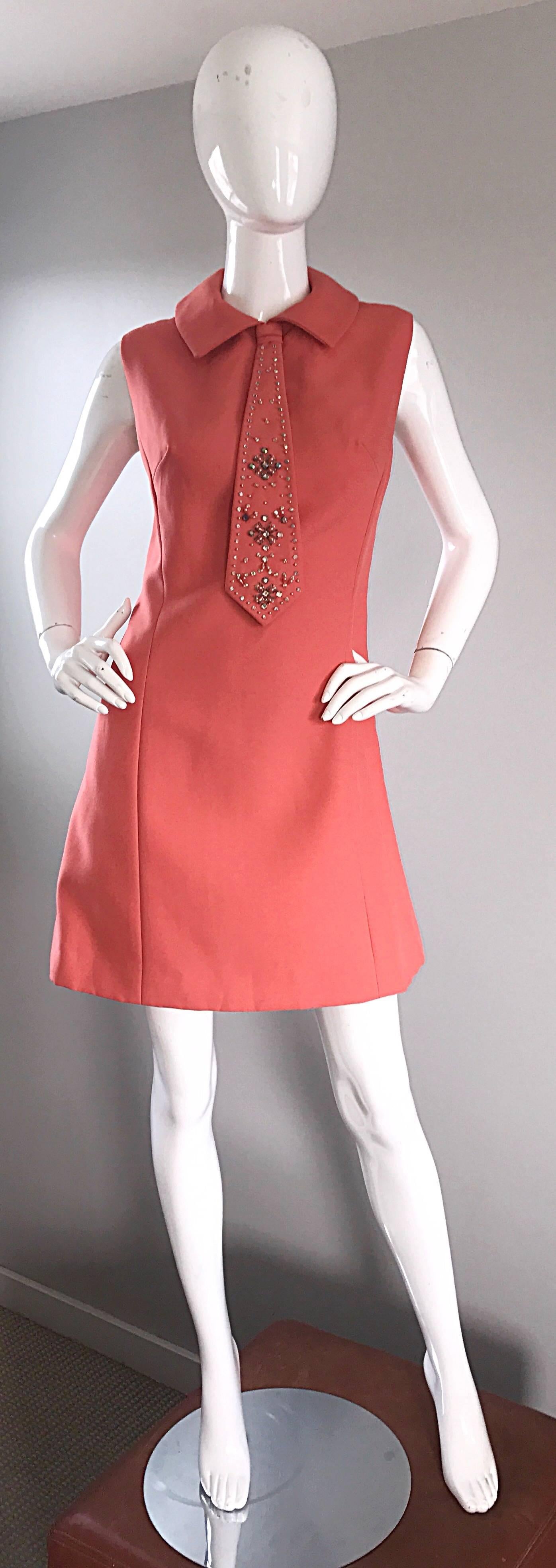 Incredibly chic 1960s coral / salmon pink colored 'necktie' A-line / shift dress! Features attached tie at the front, with dozens of beads and sequins. Flattering A-Line fit hides any flaws. Full metal zipper up the back with hook-and-eye closure.
