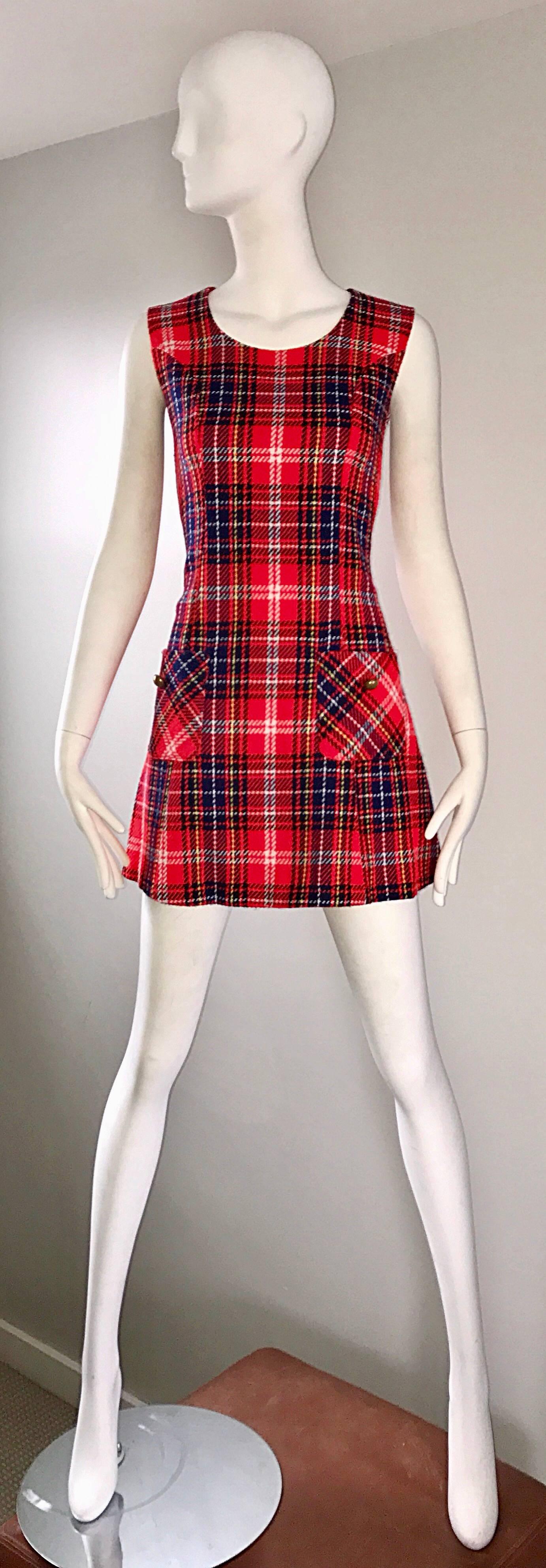 Chic 1960s tartan plaid scooter A-line dress! Features vibrant cherry red, navy blue, and yellow plaid throughout. Pocket at each side of the waist, with a brass gold button on each. Full metal zipper up the back with hook-and-eye closure. Flirty