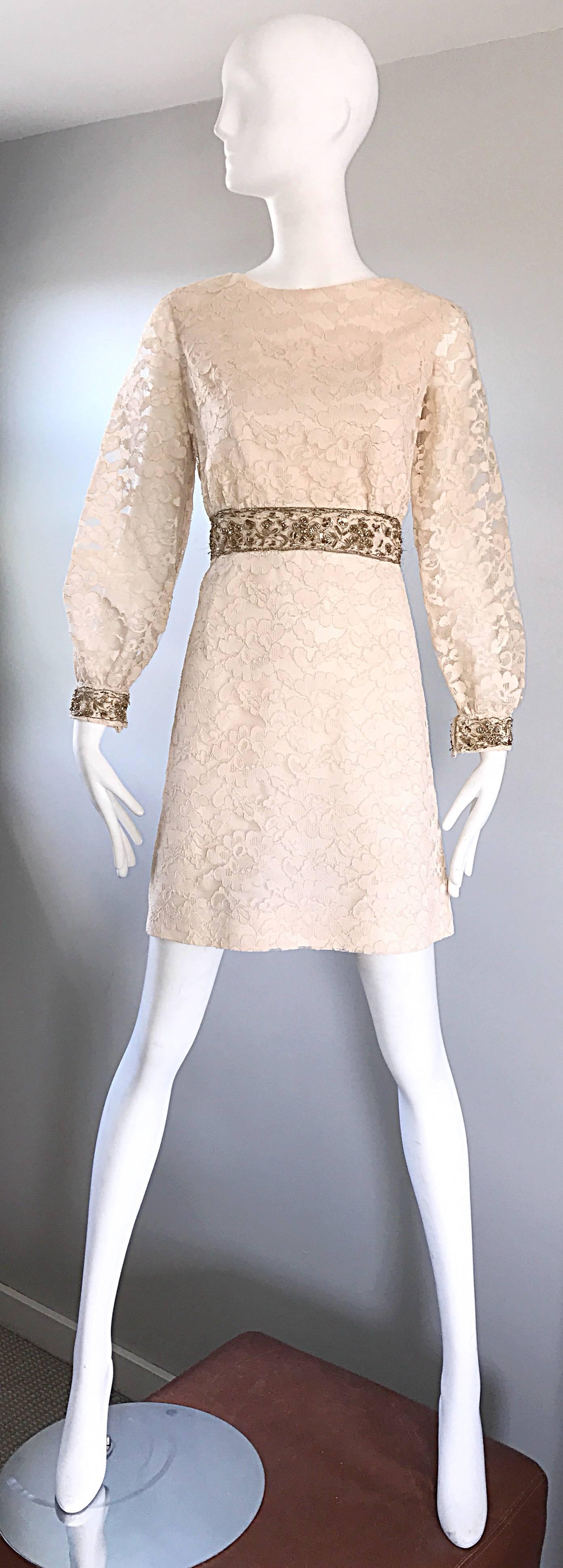 Chic 1960s ivory and gold lace A-line dress! Features a fitted bodice, with a nice full flattering flared skirt. Gold embroidered waistband and sleeve cuffs are adorned with gold sequins, pearls and beads. Nice full sleeves with a fitted cuff that