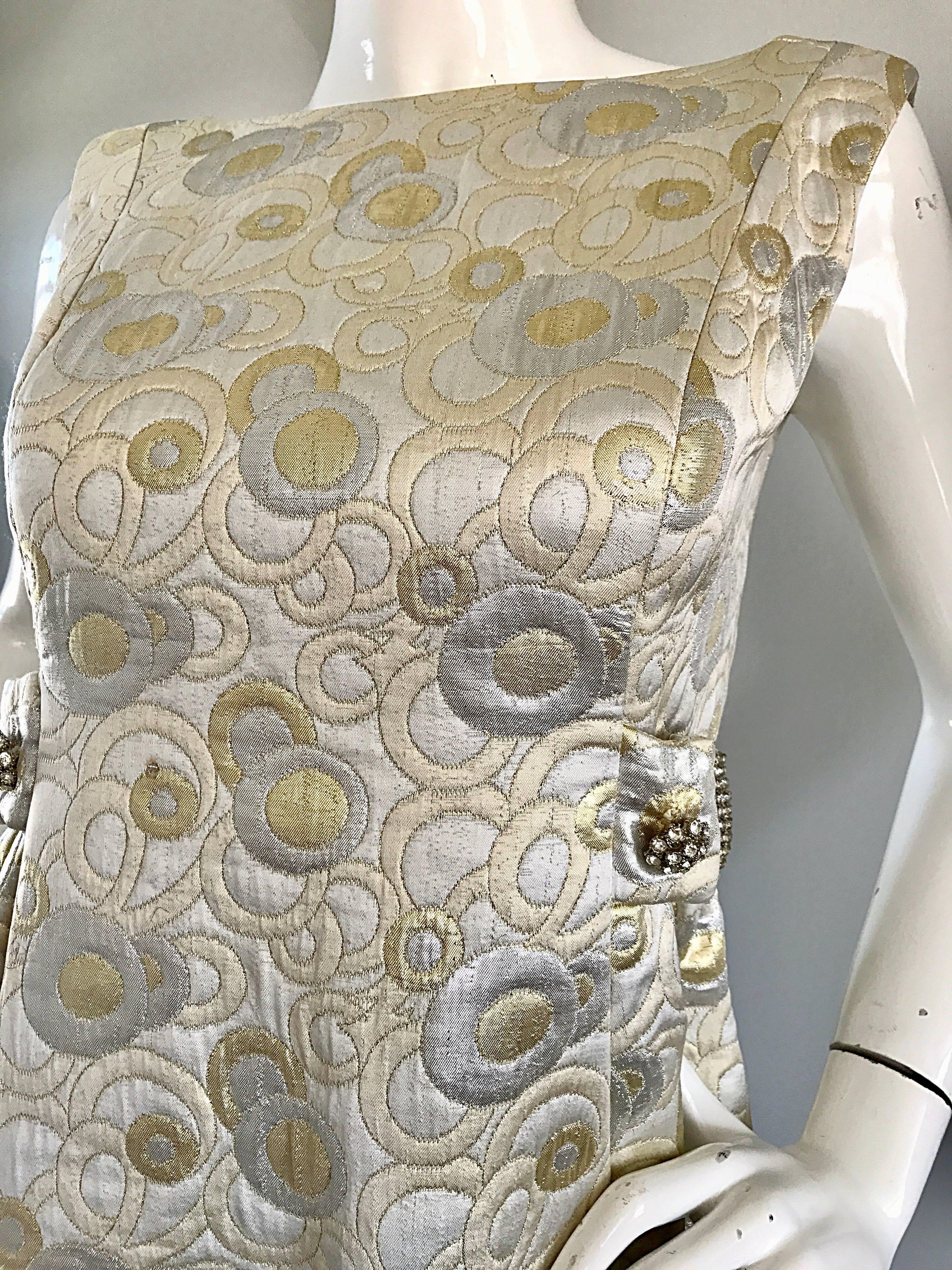 Amazing 1960s demi couture silver and gold silk brocade sleeveless evening dress! Features mod circular shapes throughout in silver and gold. Attached rhinestone belt on the back leads to rhinestones on each side of the waist. Sleek tailored bodice,