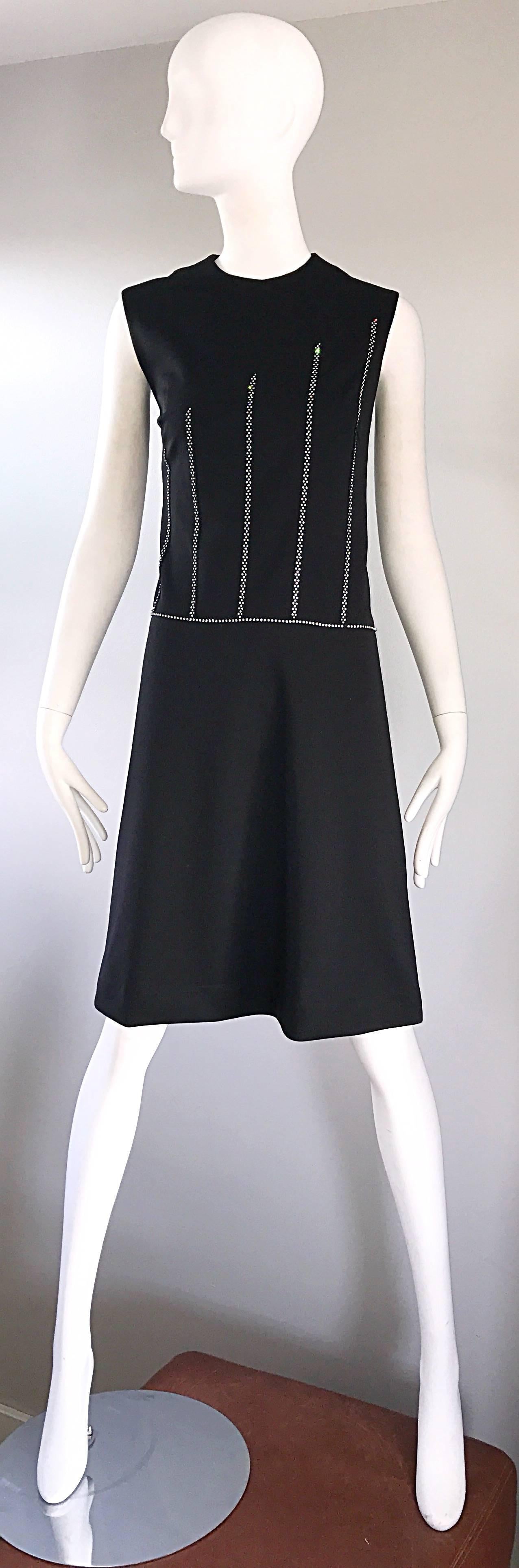 Chic 60s black Italian knit shift dress, with asymmetrical rhinestones encrusted throughout the front. Vertical strips of rhinestones get shorter from left to right. Horizontal strip of whiinestones at waist. Hidden zipper put he back with