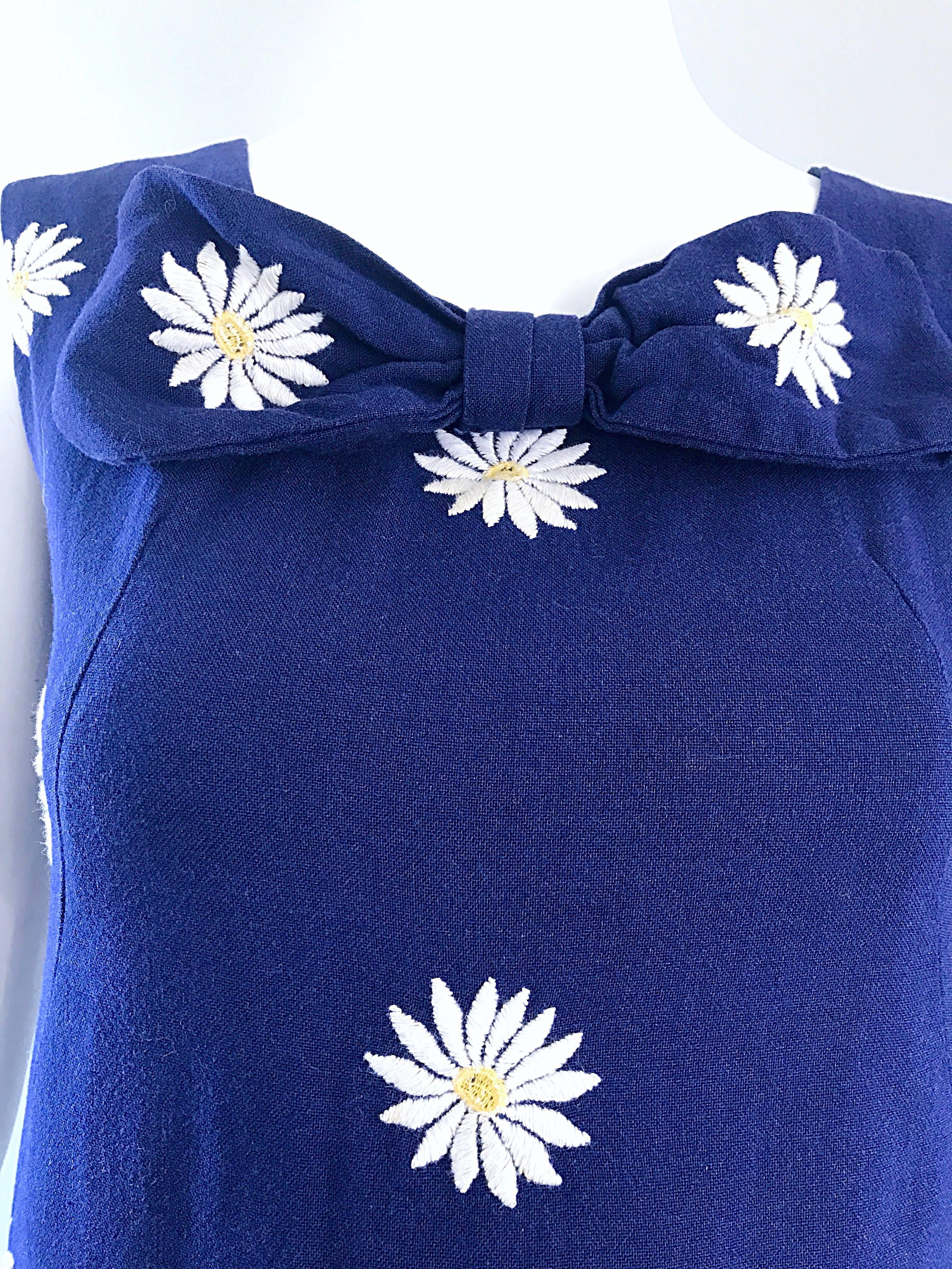 Chic 1960s navy blue cotton daisy print sleeveless shift mini dress! Features embroidered daisies throughout the entire dress. Attached bow detail at neck. High quality toon that holds shape nicely. Full metal zipper up the back with hook-and-eye