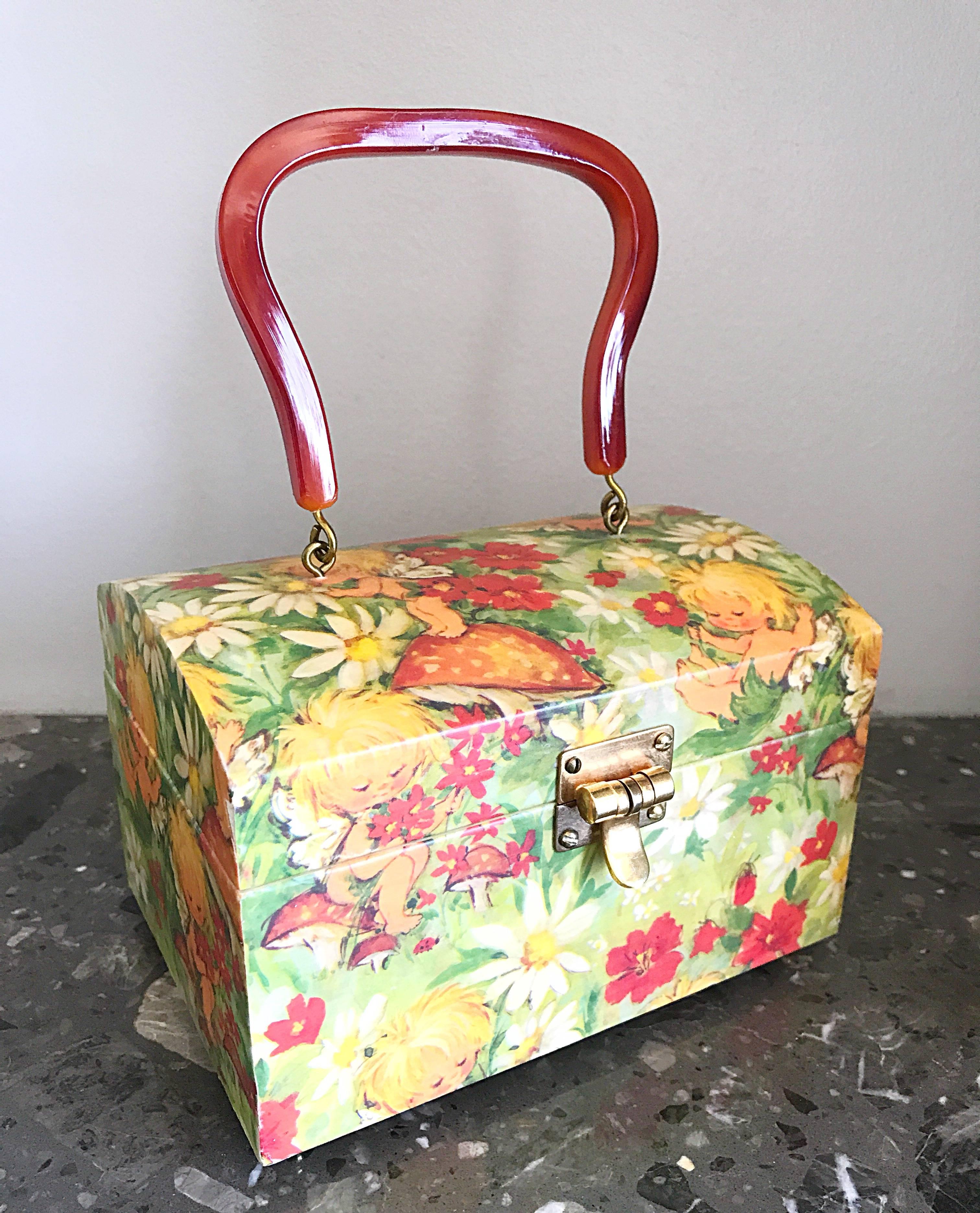 Rare mid 1970s ILEENE REEVES hand painted plexiglass novelty handbag! Features fairies, flowers, mushrooms and daisies throughout. Secure front closure. Interior features a mirror on the top inside. Amber colored lucite handle. The perfect size to
