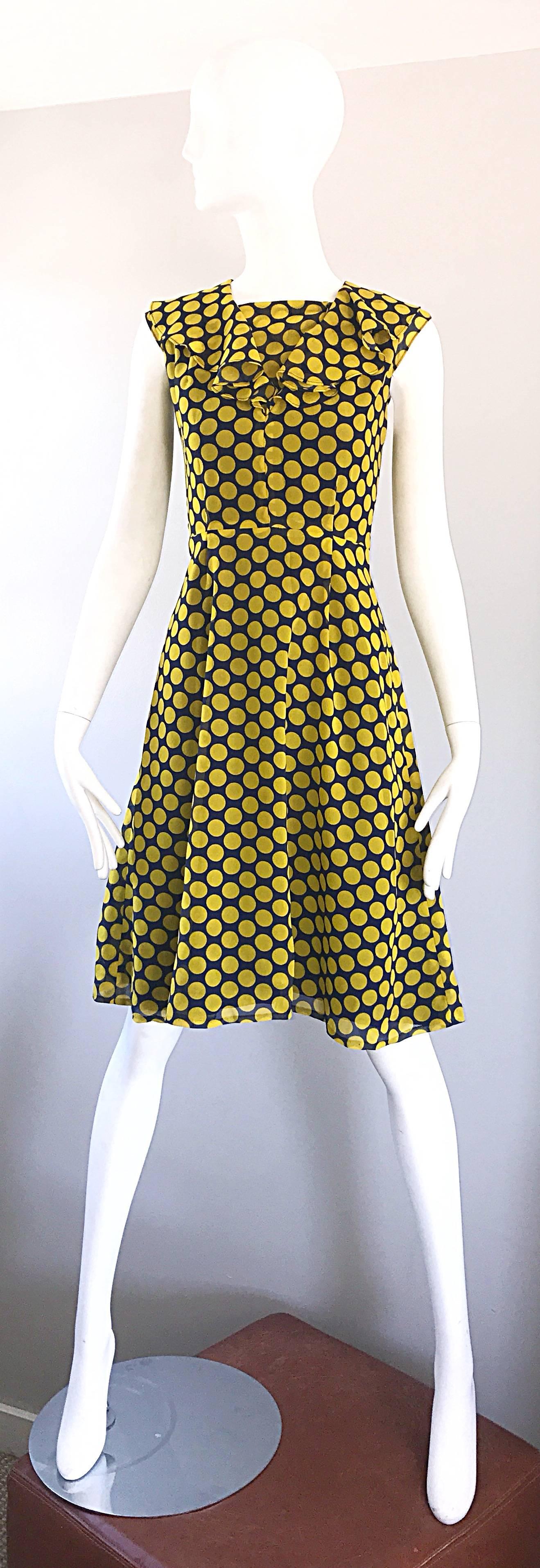 Chic early 1970s navy blue and yellow / marigold polka dot ruffle A-Line dress! Features navy polka dots throughout, with a ruffled neck. Hidden snaps shut the panel above the bust. This panel can be left undone, and flows with the ruffles. Fitted