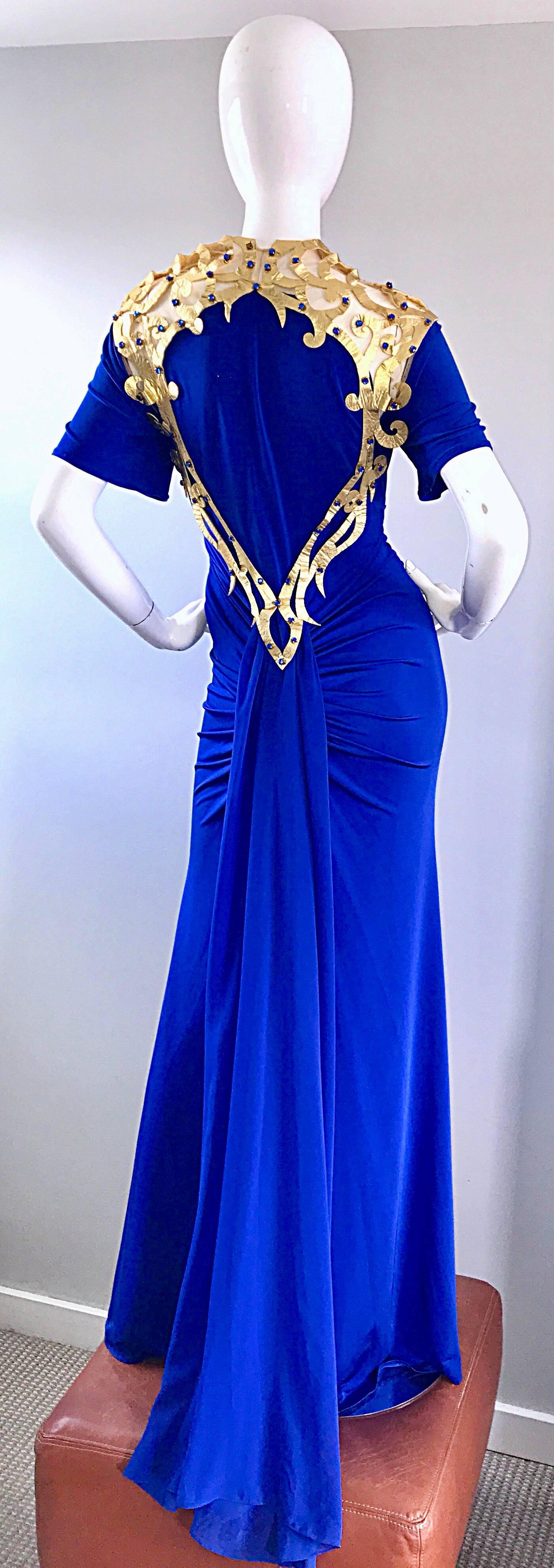 Amazing vintage royal blue jersey and gold leather caged gladiator style designer couture evening dress! Features slinky royal blue ruched jersey that stretches to fit. Gold leather cut-out collar that leads down the back. Blue rhinestones hand-sewn