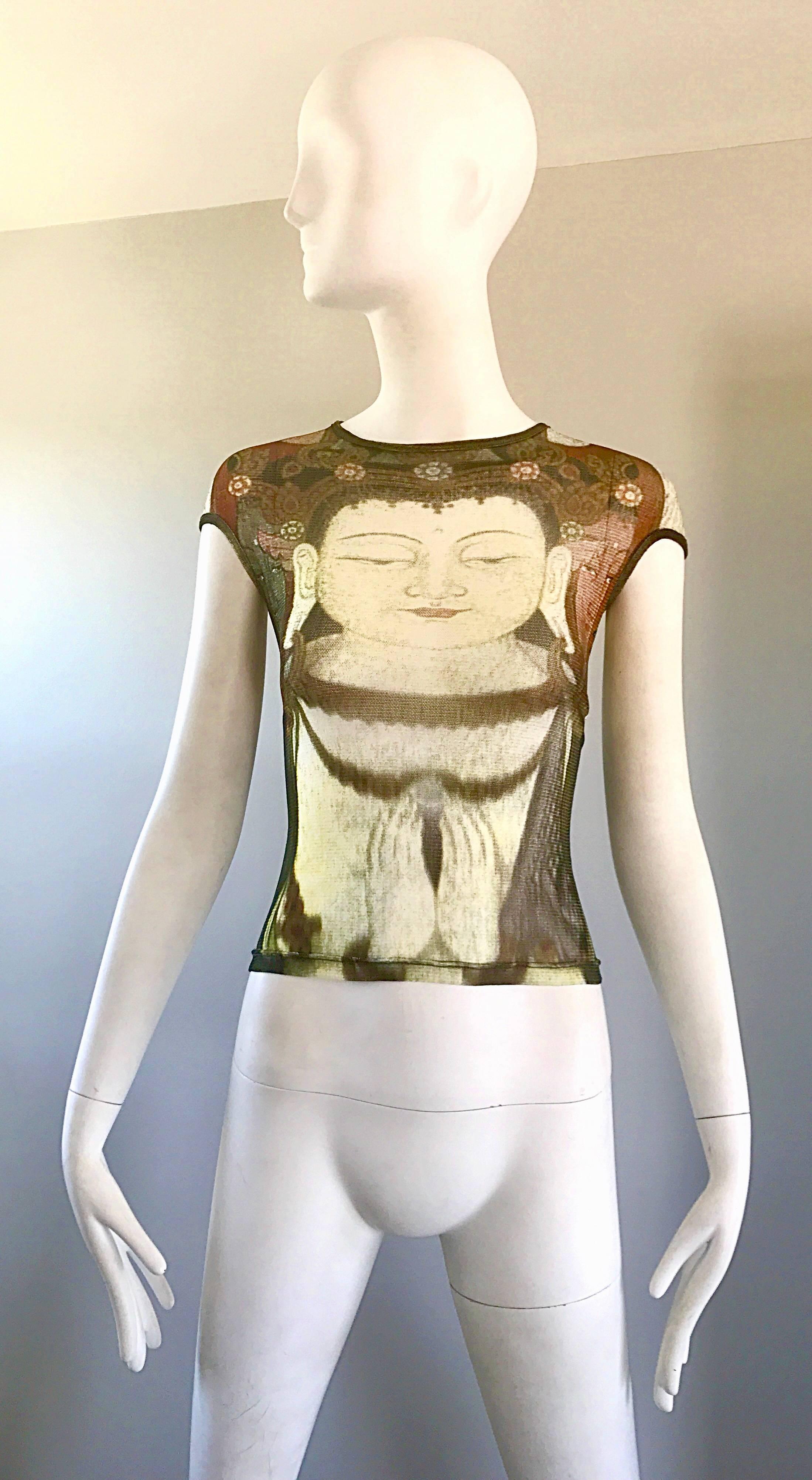 Rare 1990s VIVIENNE TAM semi sheer top from the coveted Buddha collection! Features a Buddha print on the front and back. Chic cap sleeves. Warm hues of burnt orange, blue, brown, ivory, and gray throughout. Fantastic flattering fit stretches to