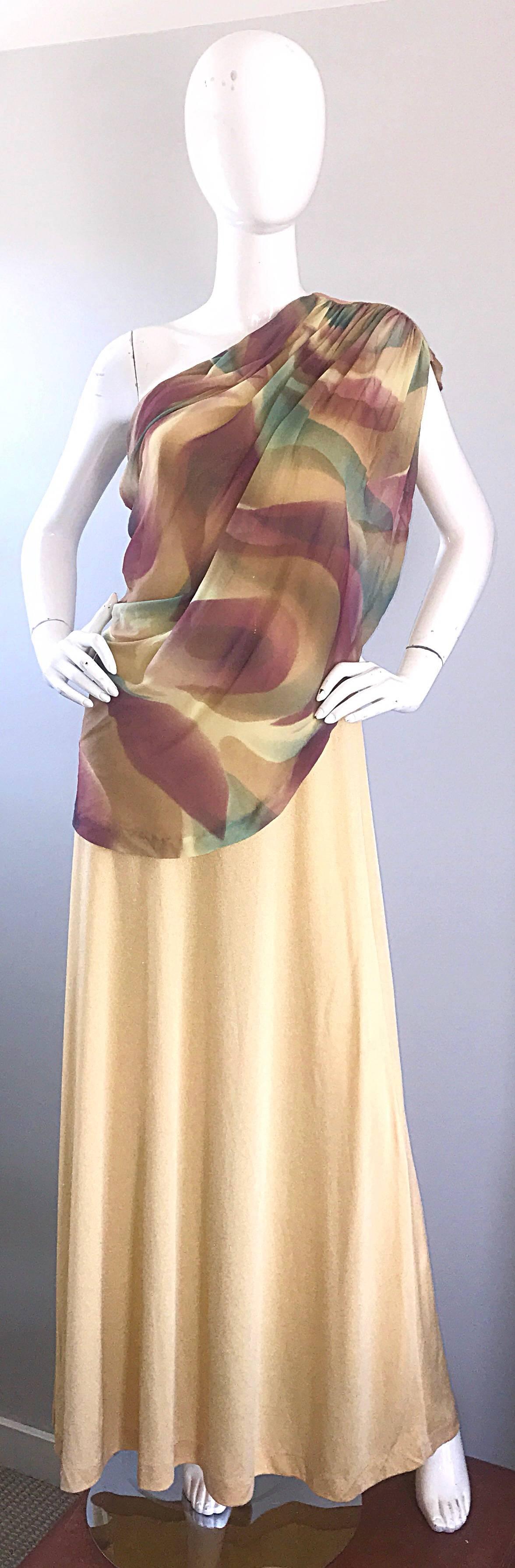 Unbelievable 1970s JOY STEVENS one shoulder Grecian gown! Features a golden jersey body with plenty of stretch. Chiffon overlay features purple, green and gold abstract print. Hidden zipper up the side with hook-and-eye closure. Great with sandals