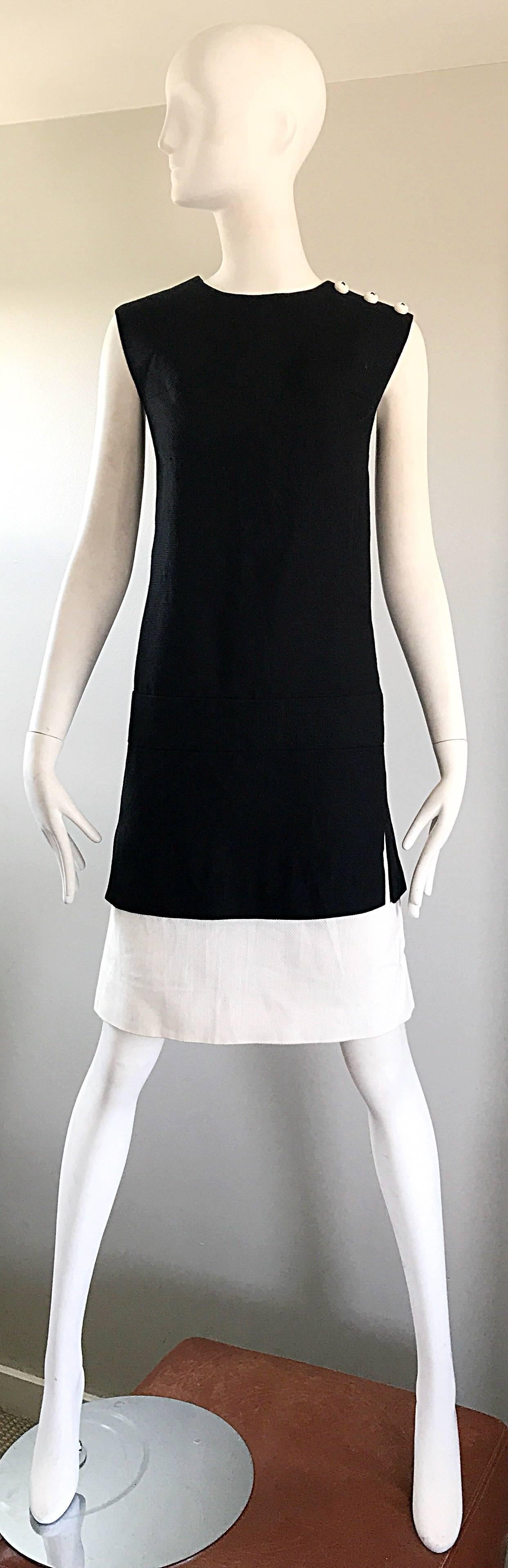 Chic 1960s HOWARD WOLF black and white cotton and linen blend shift dress! Classic shift shape, with just the right amount of added flair! Three white mock round buttons at the left shoulder. White panels under the skirt peek through the slits at