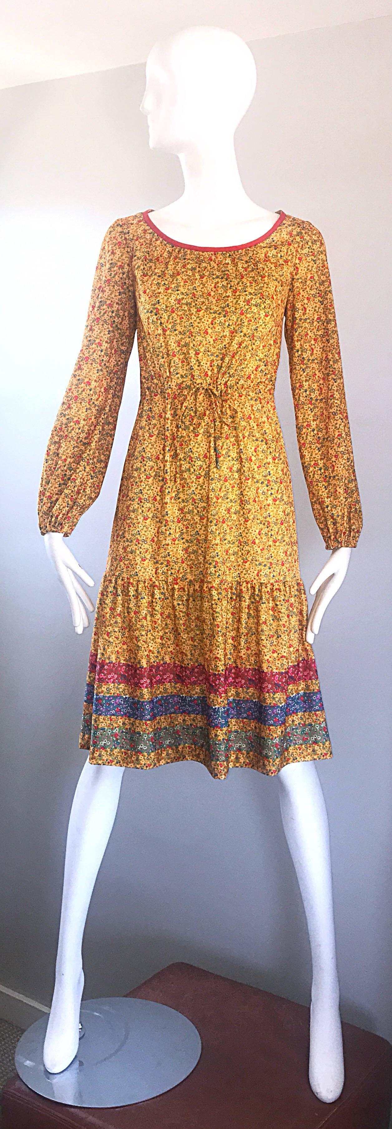 Chic 1970s yellow flower and stripe printed long sleeve boho prairie jersey dress! Fitted bodice with a drawstring waist and A line skirt. Long sleeves feature elastic at each cuff, so can easily be worn with sleeves up. Mini flowers in red, blue