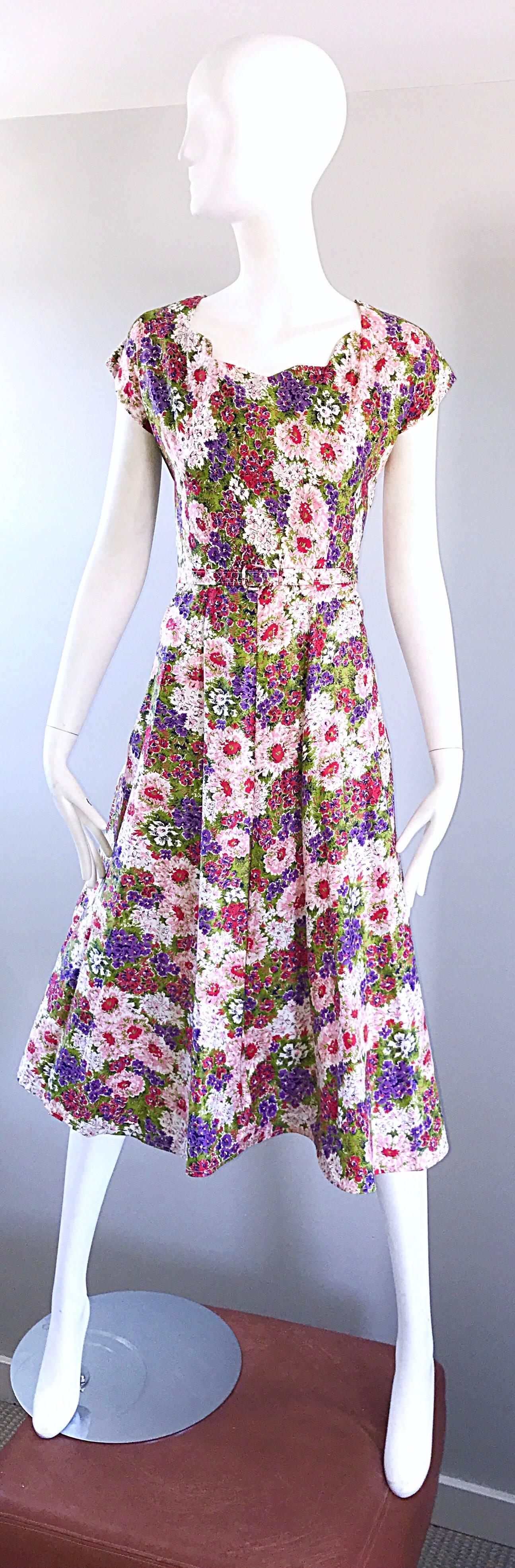 Gorgeous 1950s demi couture flower printed rhinestone encrusted scalloped neck cotton fit n' flare dress! Features vibrant colored floral print in purple, red, pink, green and white. Rhinestones hand-sewn above the bust, below the scallops.