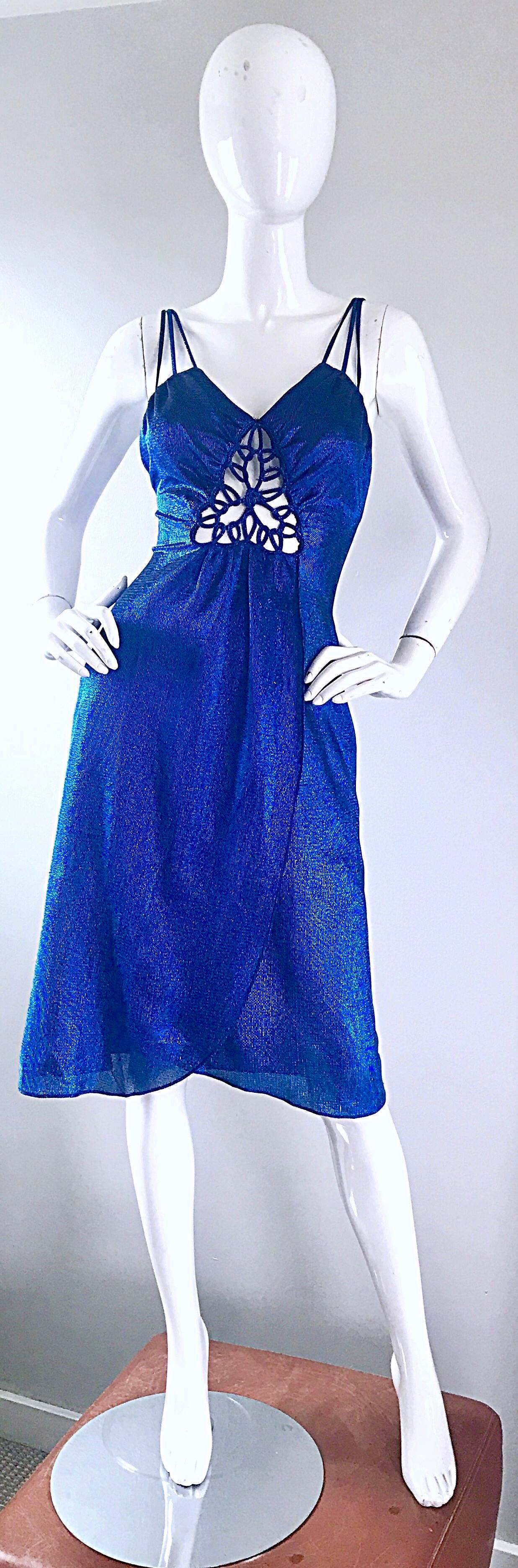 Sexy 1970s SAMIR electric blue metallic slinky cut-out dress! Features an intricately cut-out detail at center bust. Hidden zipper up the back. Three straps at each shoulder. Flattering flirty wrap style skirt, with a fitted bodice. Looks amazing