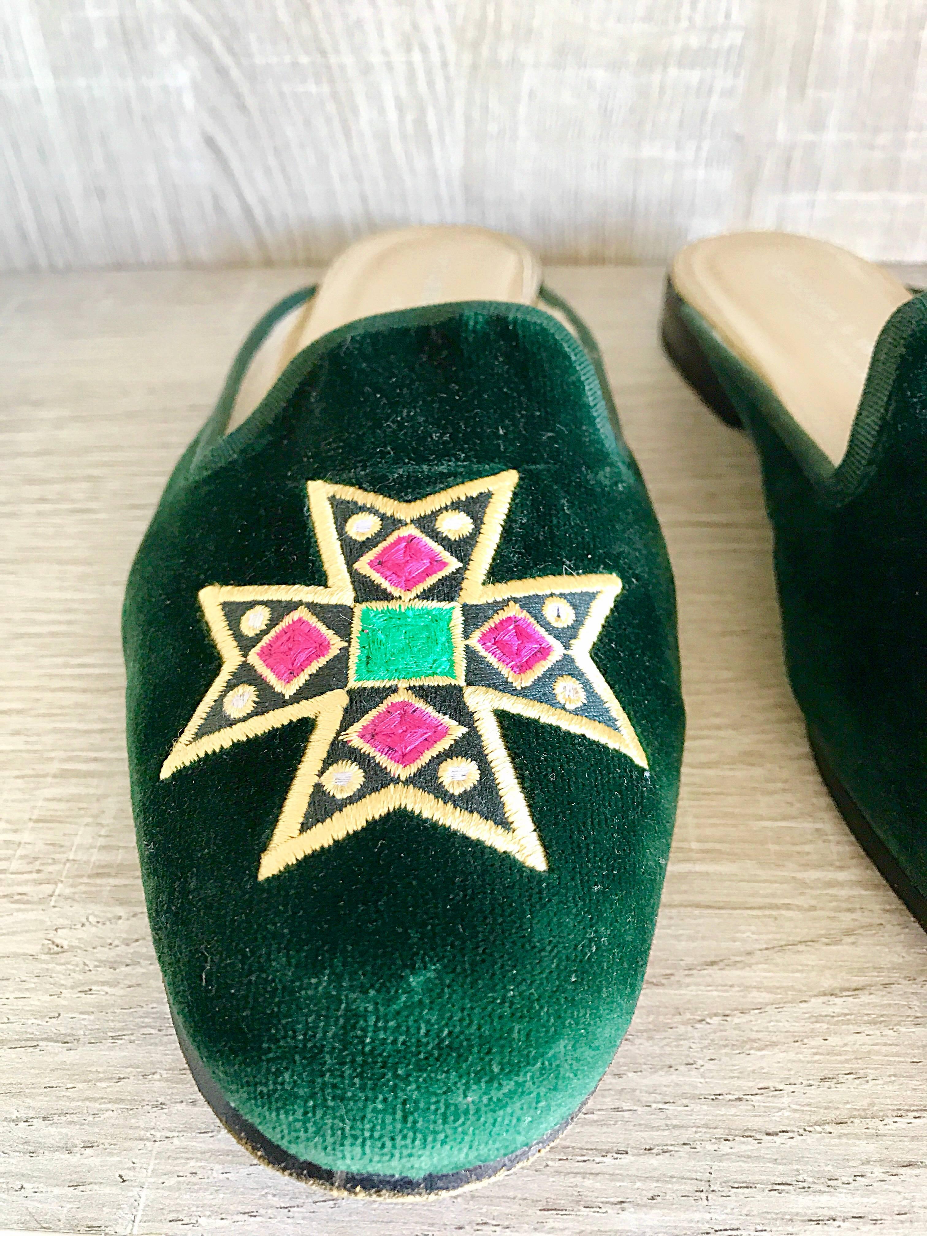 From one of the brand's first collections (1993) comes these fabulous vintage 
STUBBS & WOOTTON forest green velvet flats / slides! Features a hand embroidered crest in fuchsia, emerald green, and yellow on each shoe. Signature style from a hard to