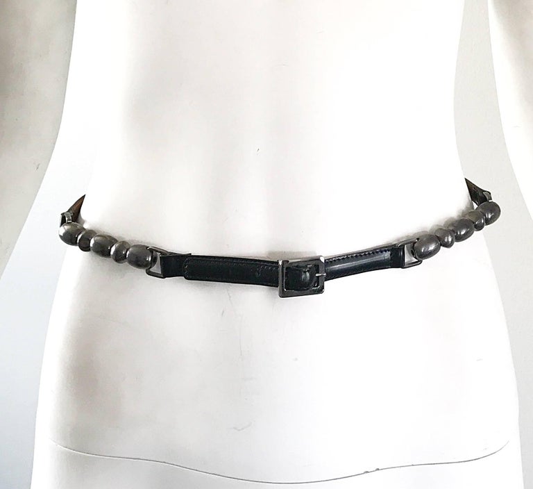 Tres chic JOHN GALLIANO for CHIRSTIAN DIOR late 90s black and gunmetal skinny belt! Features black leather, with a gunmetal round 'balls' plaque on each side of the front. Has just the right amount of hardware to add that little something special to
