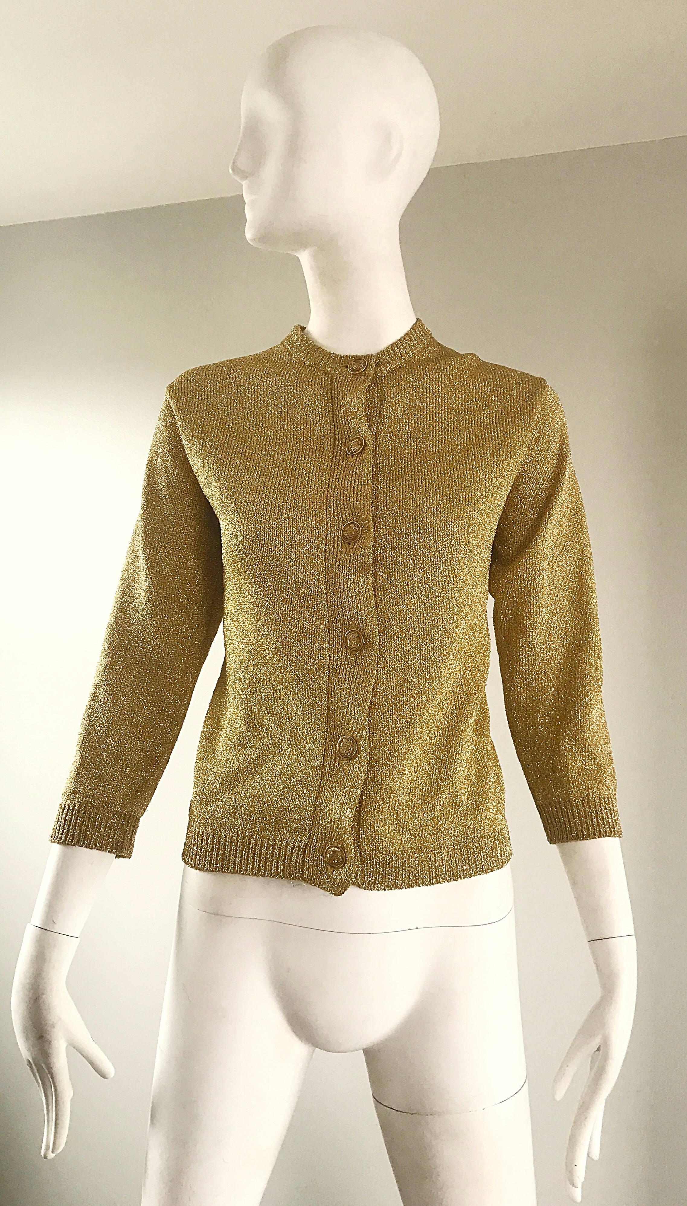 Pull cardigan chic des années 1950 en lurex métallique or à manches 3/4 ! Six boutons en métal doré sur le devant, avec fermeture cachée par crochets et œillets sur le haut du col. Fantastique coupe ajustée. Une construction fantastique avec