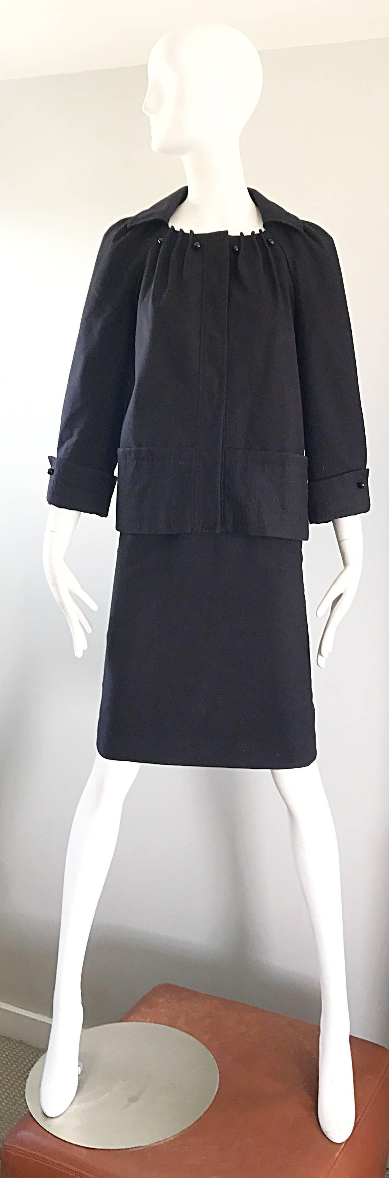 Classic and chic 90s does 60s ALBERTA FERRETTI black virgin wool skirt suit! Jacket features a pillbox / swing silhouette. Pleated details around the collar, with round black lacquer buttons. Large hidden snaps up the front. Pocket at each side of