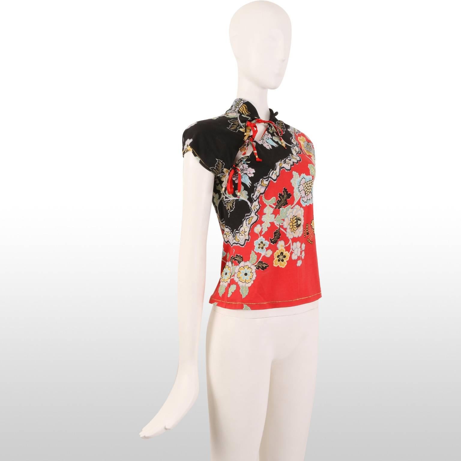 This is a Roberto Cavalli oriental style top with tie fastening. The piece is black and red, with gold glitter detailing. The body is made out of modal and the ornaments out of Silk. The Top remains in excellent condition. 