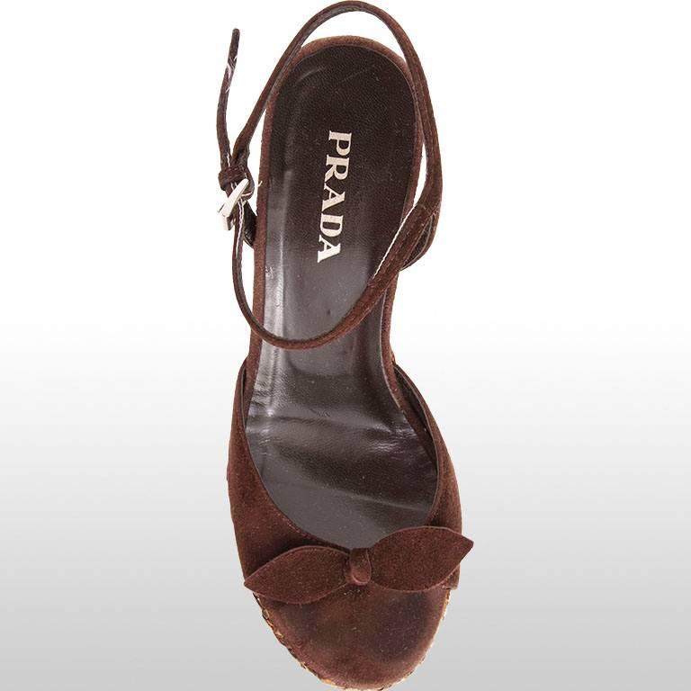 This pair of Prada wedges feature a simple bow detail and a thin strap around the ankle in brown suede that fastens with a small metal buckle. The wedge itself is made from woven rattan to create a beautiful detail, this has seen a little bit of