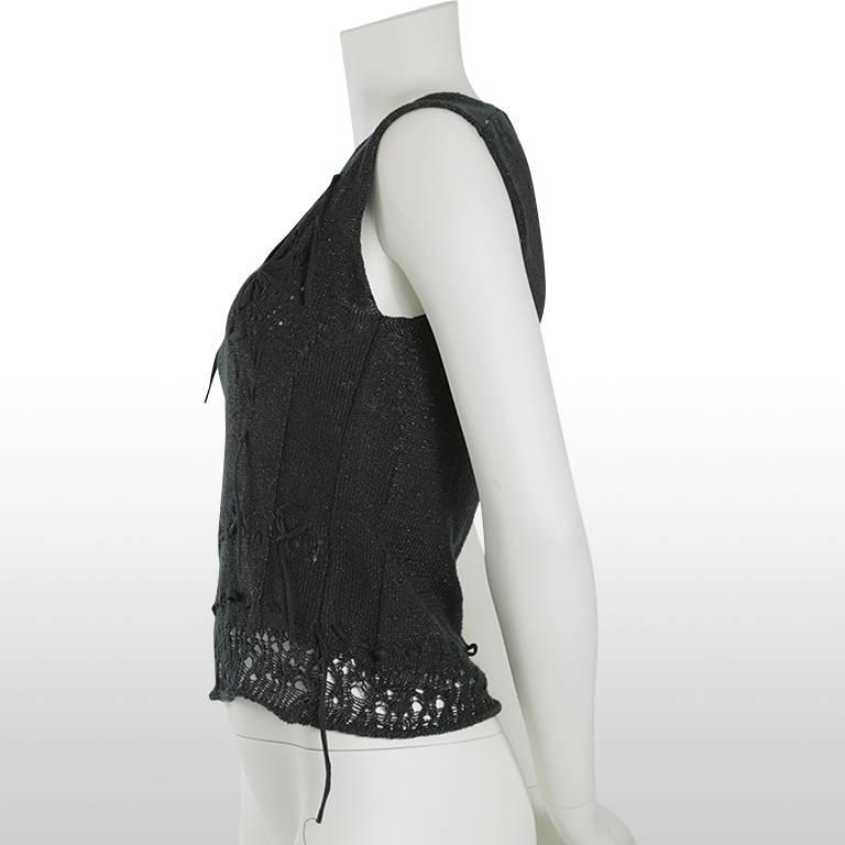 This linen blend knit is a Dries Van Noten vest with a V-necline. It is predominantly black with flecks of silver metallic fibres woven throughout. It has a black tape detail woven amongst the knit to create detail to the garment. This top is in