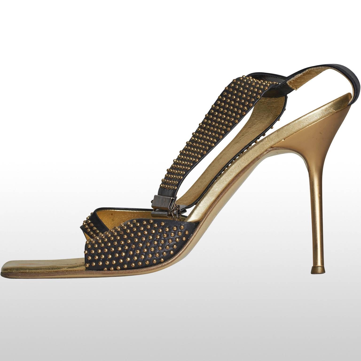 Stunning Roberto Cavalli black sandals with stiletto gold heel and gold studs. The shoes have a unique chain fastening which hooks at the front of the ankle, thus it is a desirable and original design. Ideal for party or evening attire, adding a
