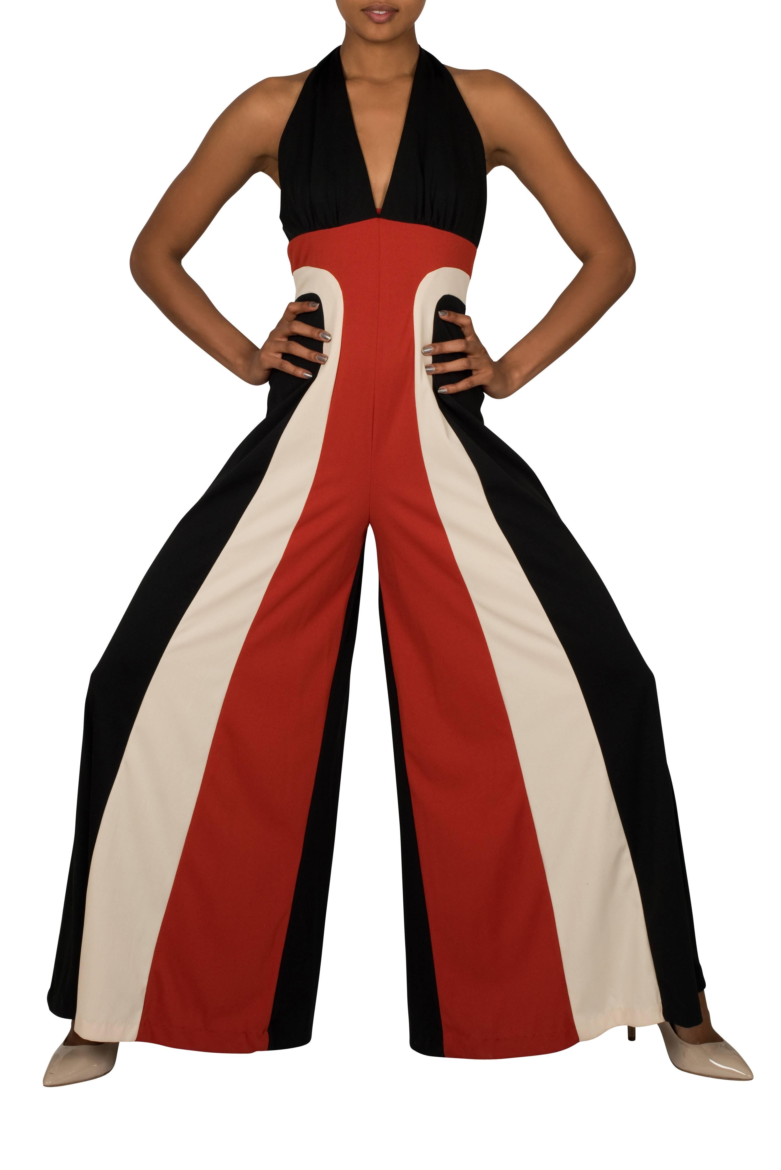 Stunning statement racing stripe jumpsuit from the 1970's. Featuring a bold design with red and ivory stripes inserted in the centre front of the black polyester jersey which ties at the nape of the neck forming the halter neck shape. This jumpsuit