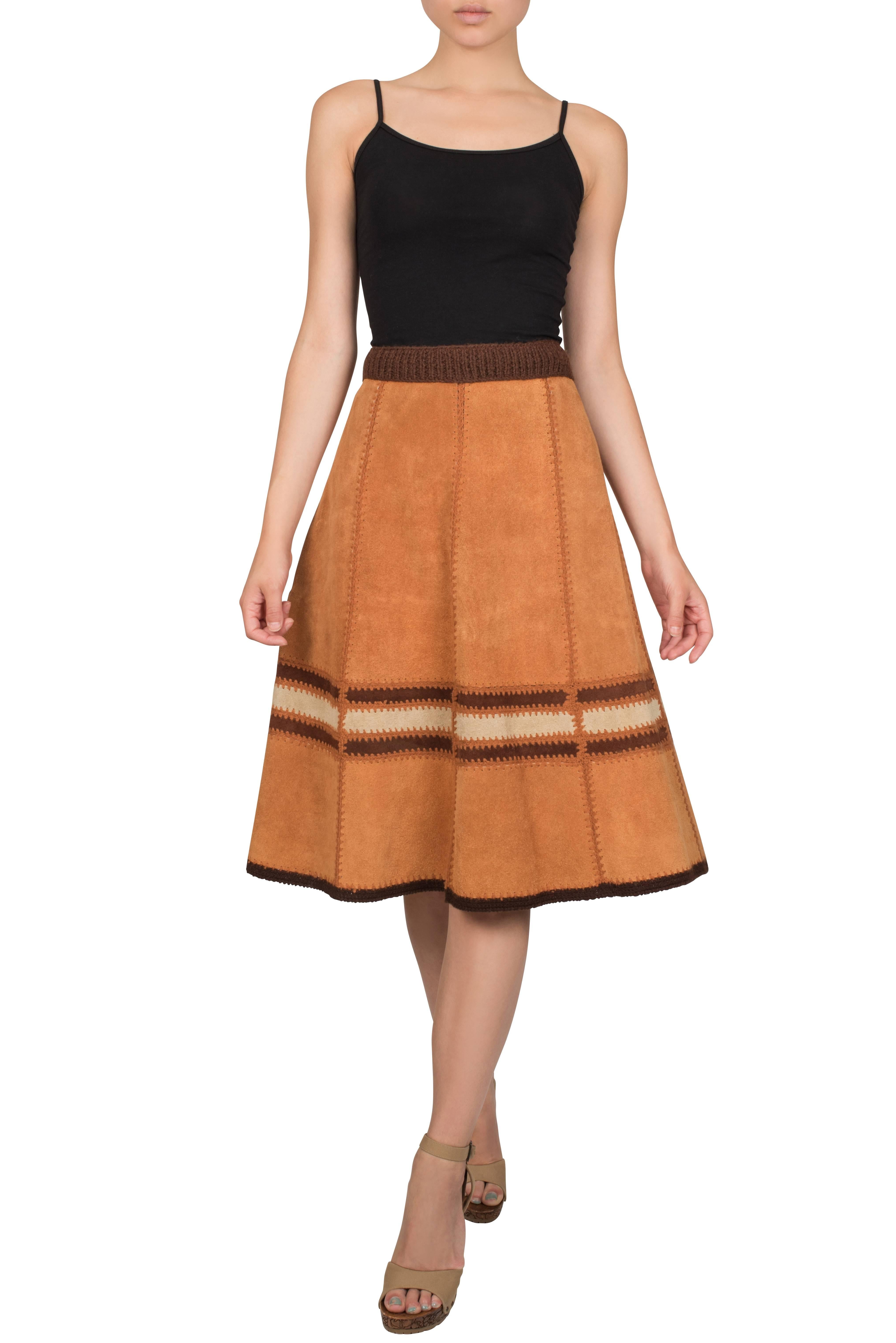 Western style caramel suede skirt made from panels which are stitched together in caramel colour thread. The waistband is made from a thick crochet band, which is also present at the edge of the hem. An off-white and brown insert embellishes the