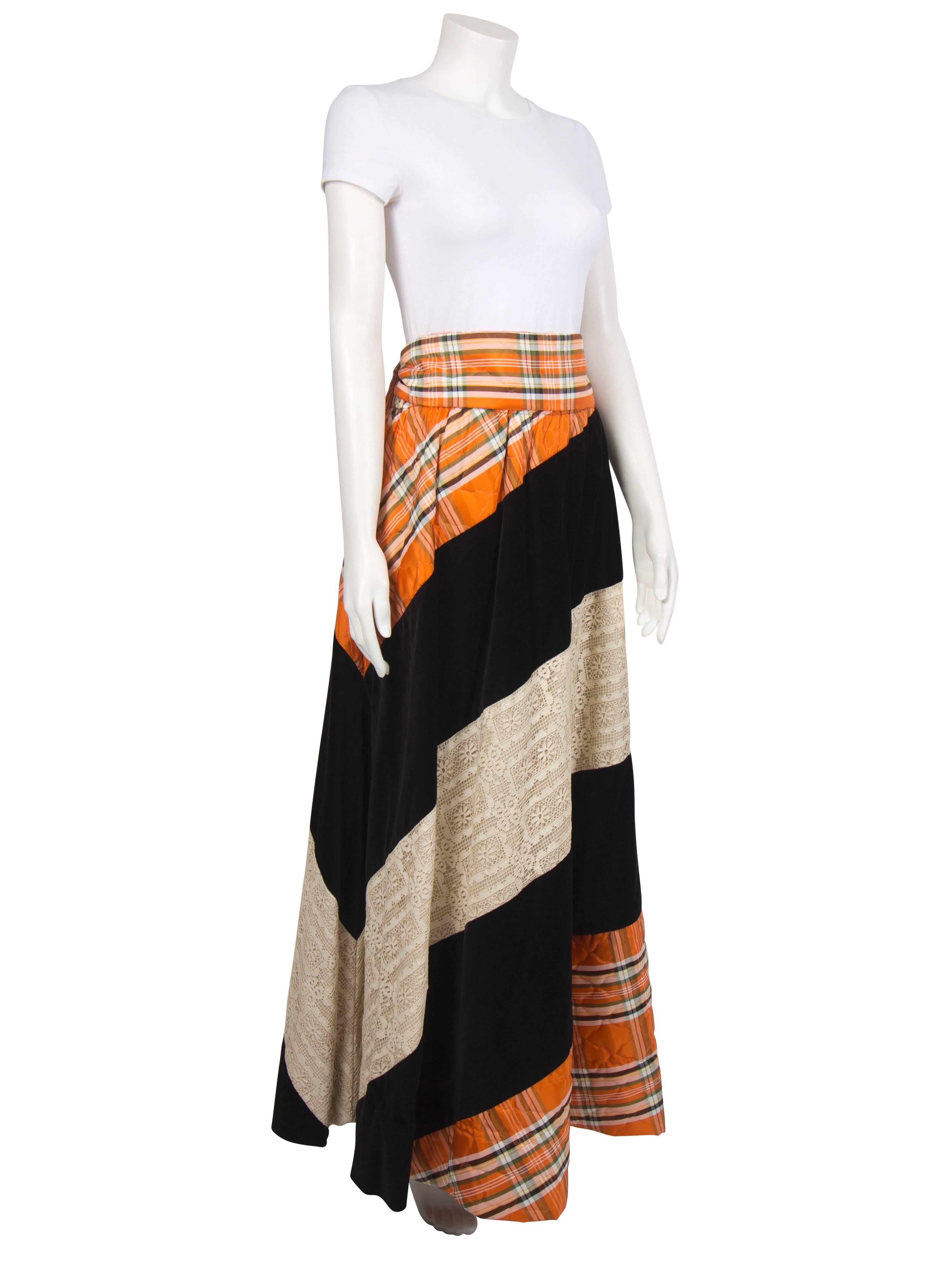 A beautiful example of Chessa Davis's signature patchwork designs, this skirt is made from diagonal panels of black velvet, cotton lace and a quilted plaid in orange and green. The skirt is lined  in soft cotton and has an elasticated waist. A wide