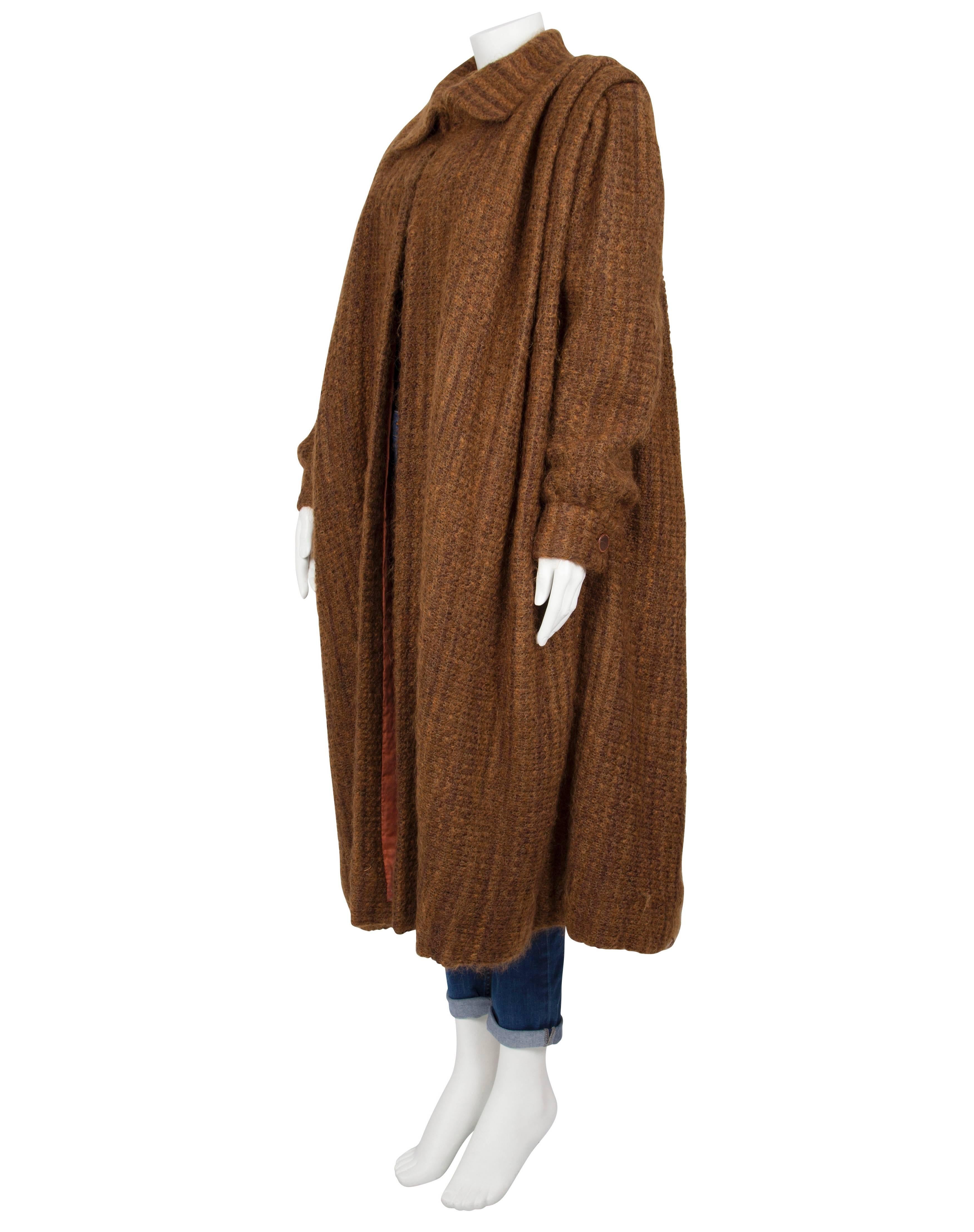 An oversized ochre boucle wool long-length overcoat by London society couturier Harald. The heavy, textured coat is softly pleated and features a wide collar, pleated shoulders and full-length leg-o’-mutton sleeves with fitted cuffs. The