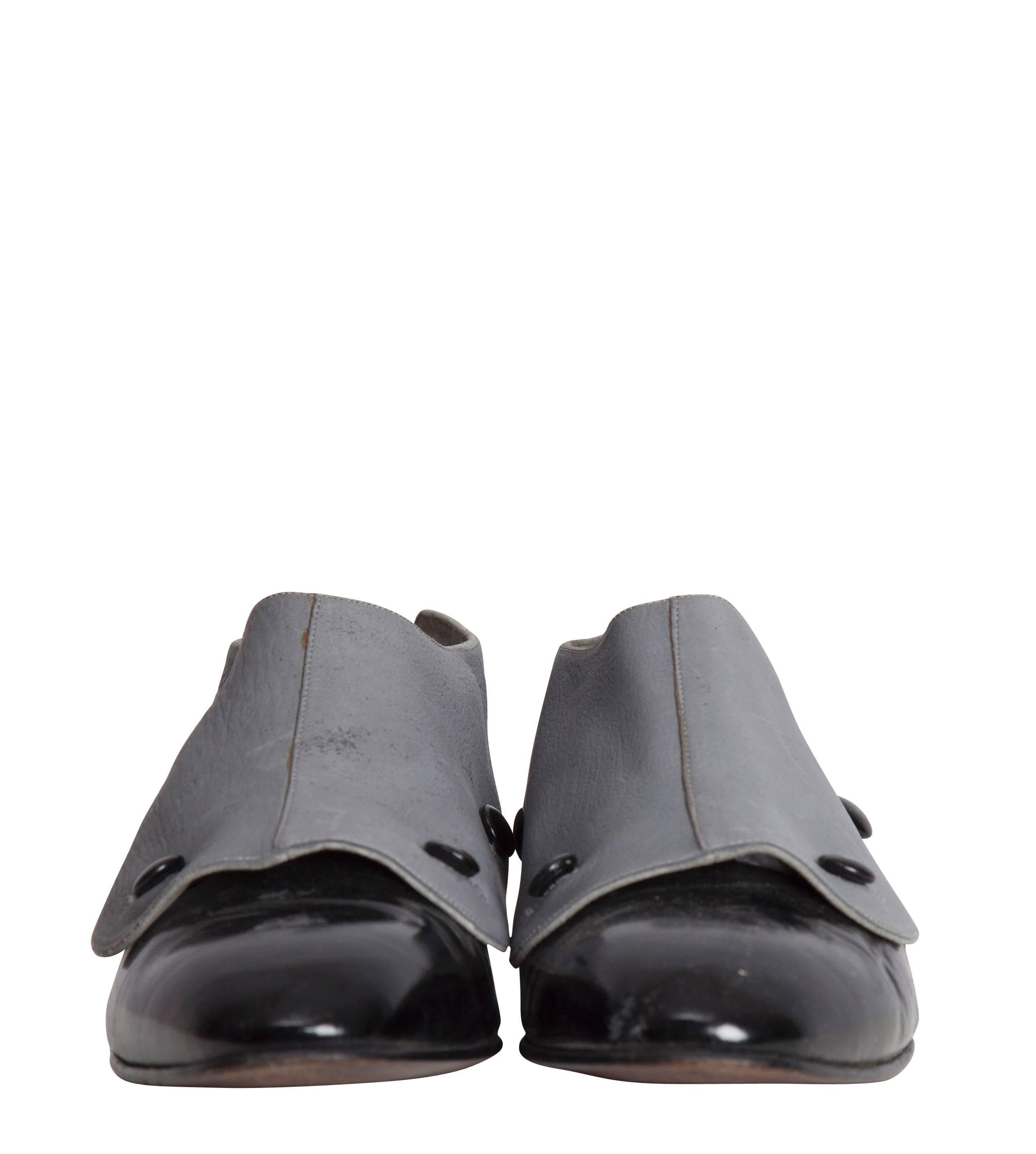 A 1985 Manolo Blahnik's versatile two-tone pair of patent leather flat shoes featuring a buttoned grey suede overlay, which when removed, reveals a pair of classic black ballet flats. A similar pair is featured in the Metropolitan Museum archive