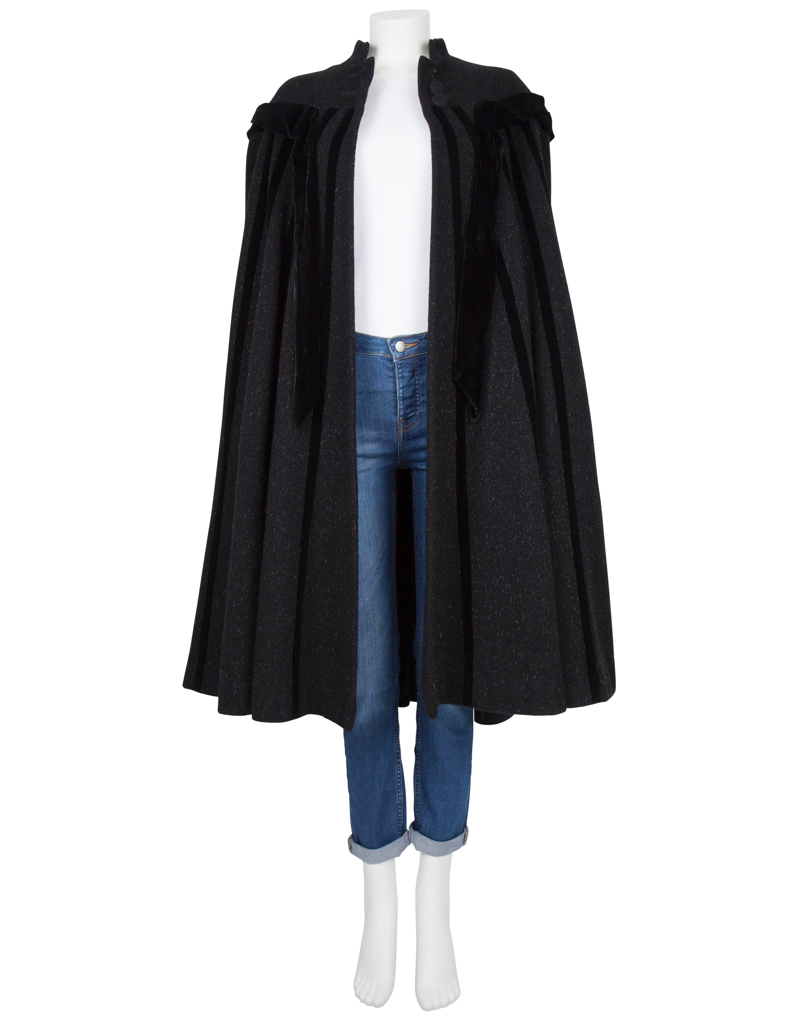 A late 1940's Lilli Ann charcoal wool coat with black velvet panelling throughout. The coat has a cape-like design with a velvet trimmed yoke from which black velvet inserts intersperse radially with the fabric forming the panels at the back. The