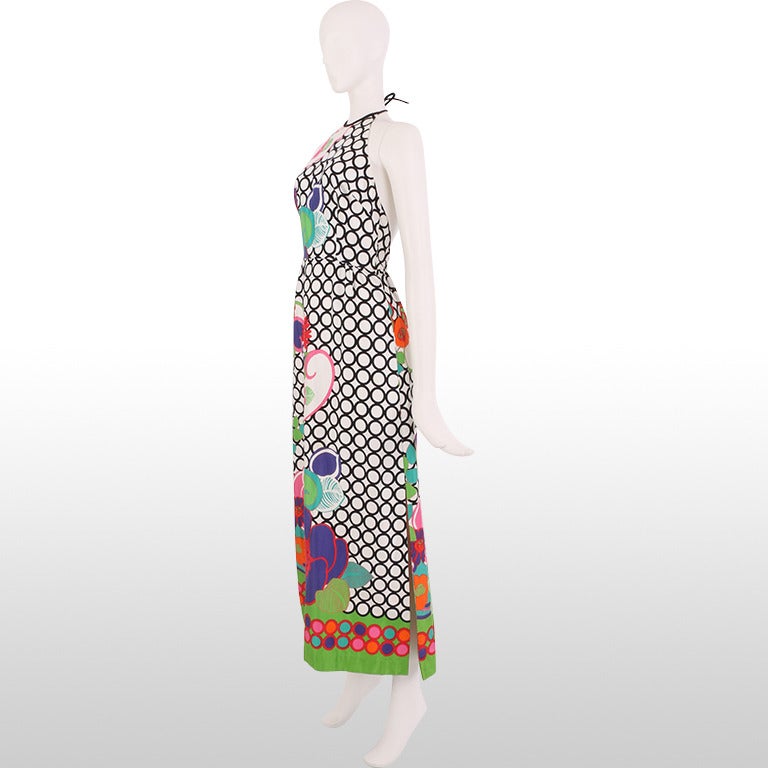 This gorgeous 1970's gown is the perfect way to turn heads this summer. It's stand-out brightly coloured print depicts large Hawaiian flowers cascading down the dress. The flowers are printed on to a geometric monochrome printed back drop allowing