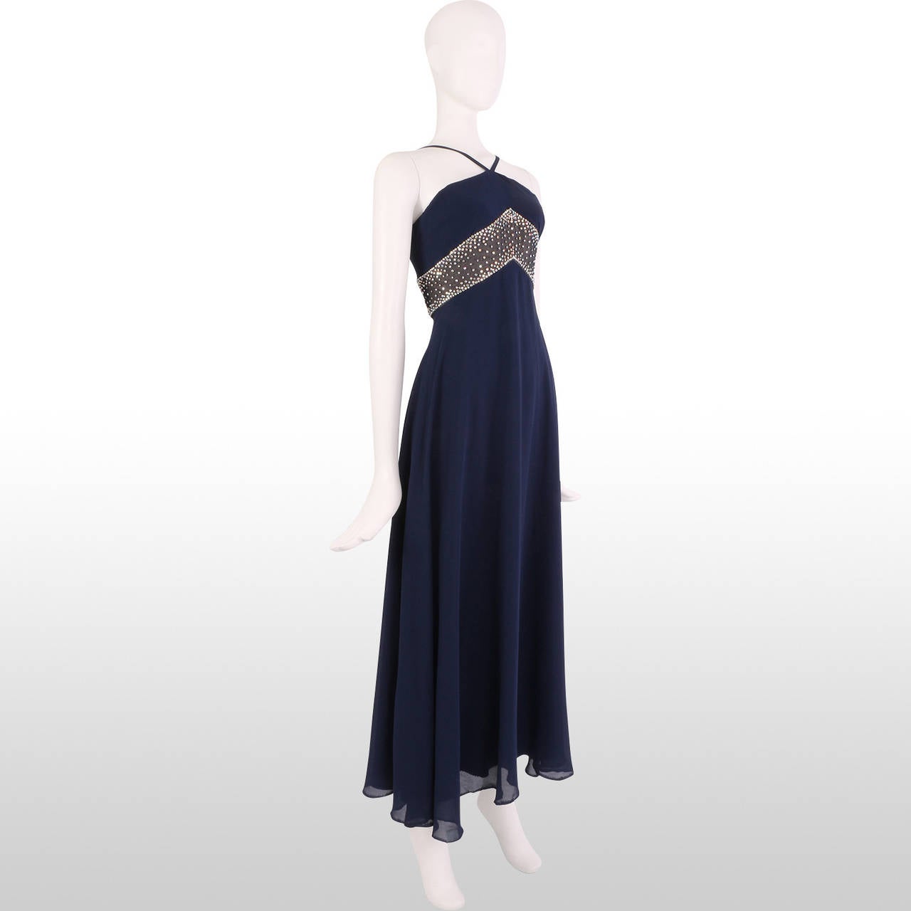 This elegant 1960's royal blue halter gown is a great piece for a special occasion. The vibrant royal blue colour is accentuated with the gem detailing which embellishes the garment just under the bust. The lightweight chiffon fabric overlay drapes
