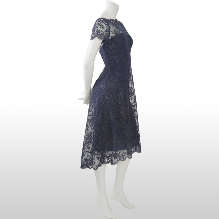 This beautiful late 1960's custom Estévez cocktail dress is beautifully made and kept. It is all navy with a strapless under-dress on top of which there is a floral lace overlay. The dress underneath the lace is boned and fitted at the bodice and