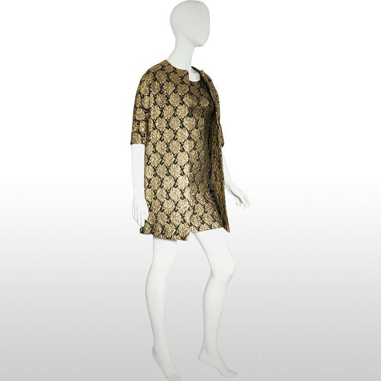 This Peggy French cocktail dress and jacket features a golden floral brocade design. The dress is fitted and petite which is complimented by a drop shoulder, half sleeve open coat. There is a center zipper at the back of the dress and both the dress