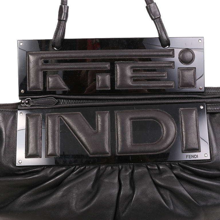 This gorgeous Fendi soft black leather handbag has two black perspex panels with leather lettering. The bag is given shape and volume with some gathering and its pouch shape. It is fastened with a zip that runs along the top of the bag and has a