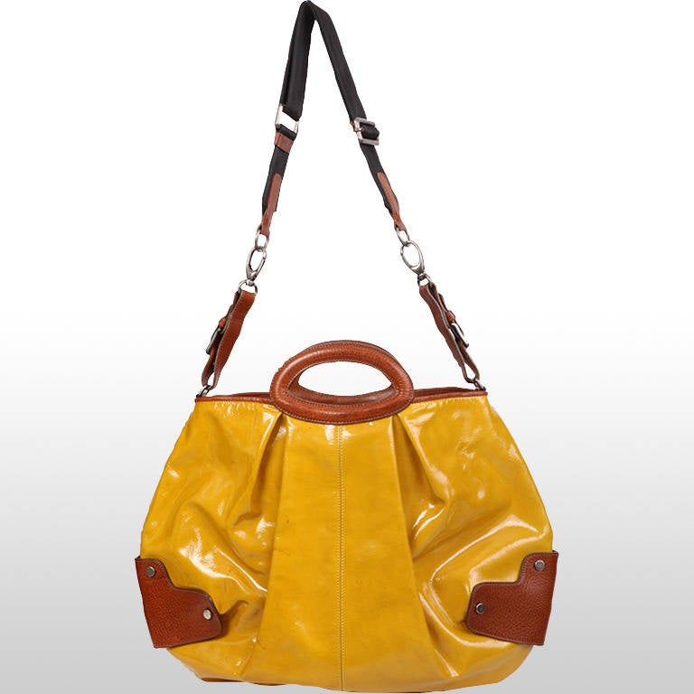 This gorgeous Marni patent mustard handbag is fun and practical in its size and capacity. The mustard yellow and the shine of the patent leather will make any outfit pop. It is made in a classic balloon bag style with a box pleat bellow the handle.